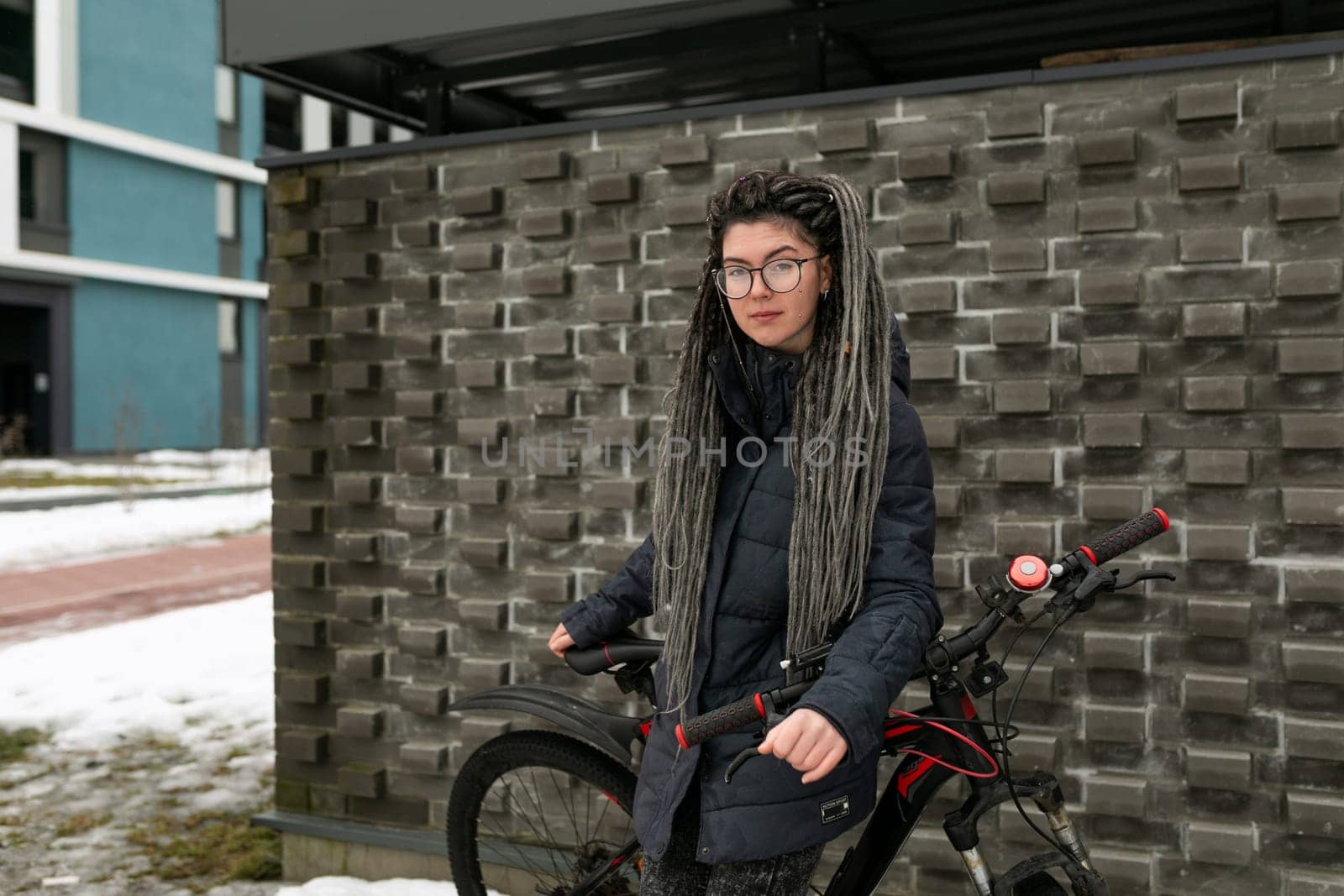Street fashion concept, young European woman with dreadlocks riding a bicycle.