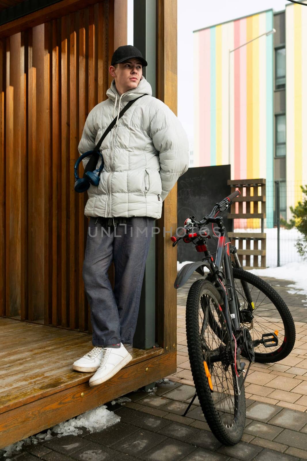 A young Caucasian man with a gray jacket and black cap rented a bicycle.