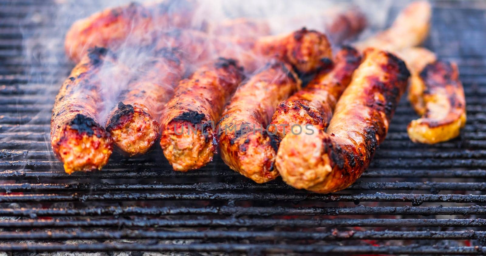 Sausages grilled on a charcoal barbeque. Top view of tasty barbecue, food concept, food on grill and detail of sausages on the grill by vladispas