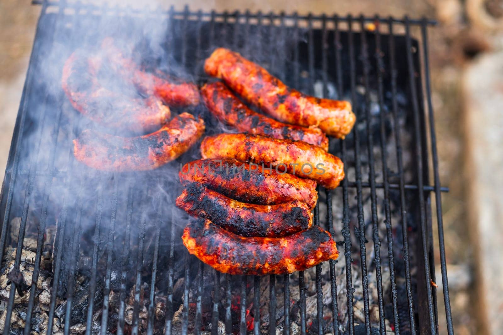 Grilling sausages on barbecue grill. Delicious sausages on charcoal grill by vladispas