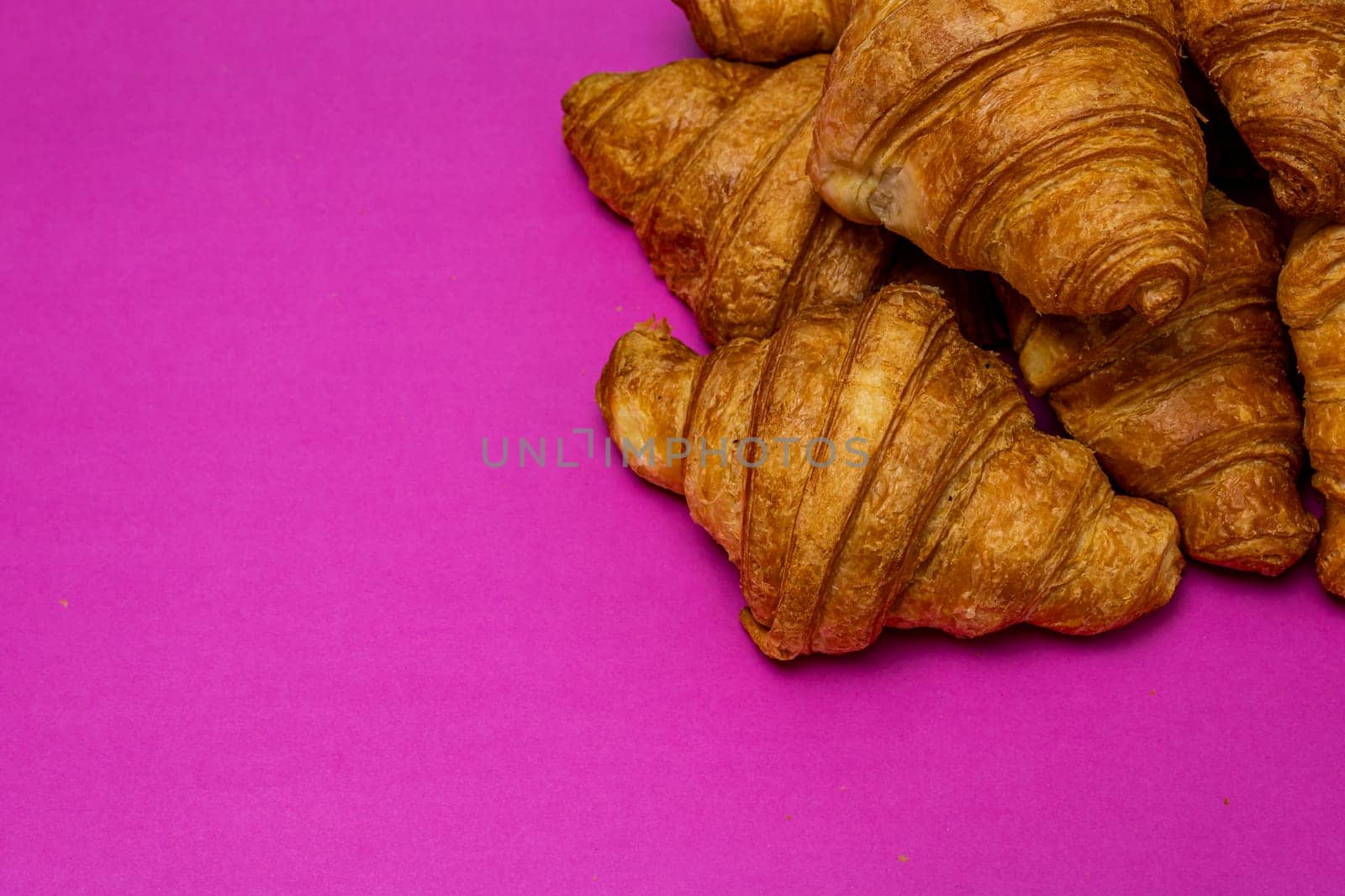  French breakfast concept. Close up of delicious, fresh croissants isolated on pink board. by vladispas