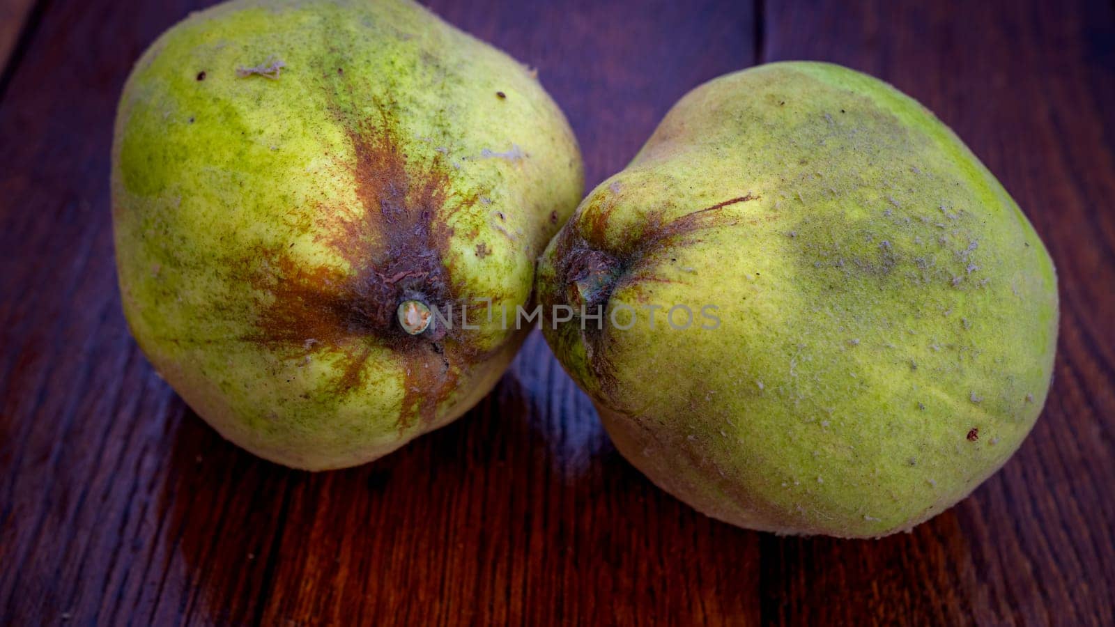Isolated quinces. Two yellow quinces on a wooden board.