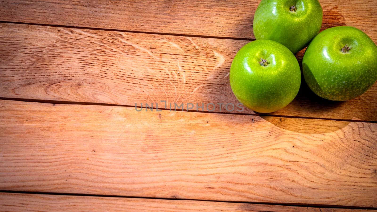 Detail on ripe green apples on wooden table. by vladispas