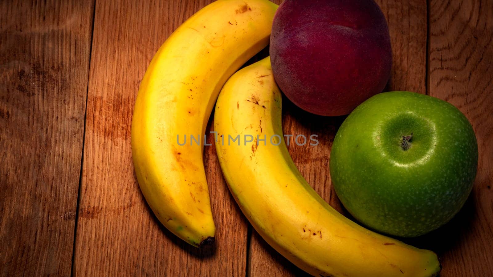 Apple, peach and bananas on a wooden board. Composition of healty fruits. by vladispas