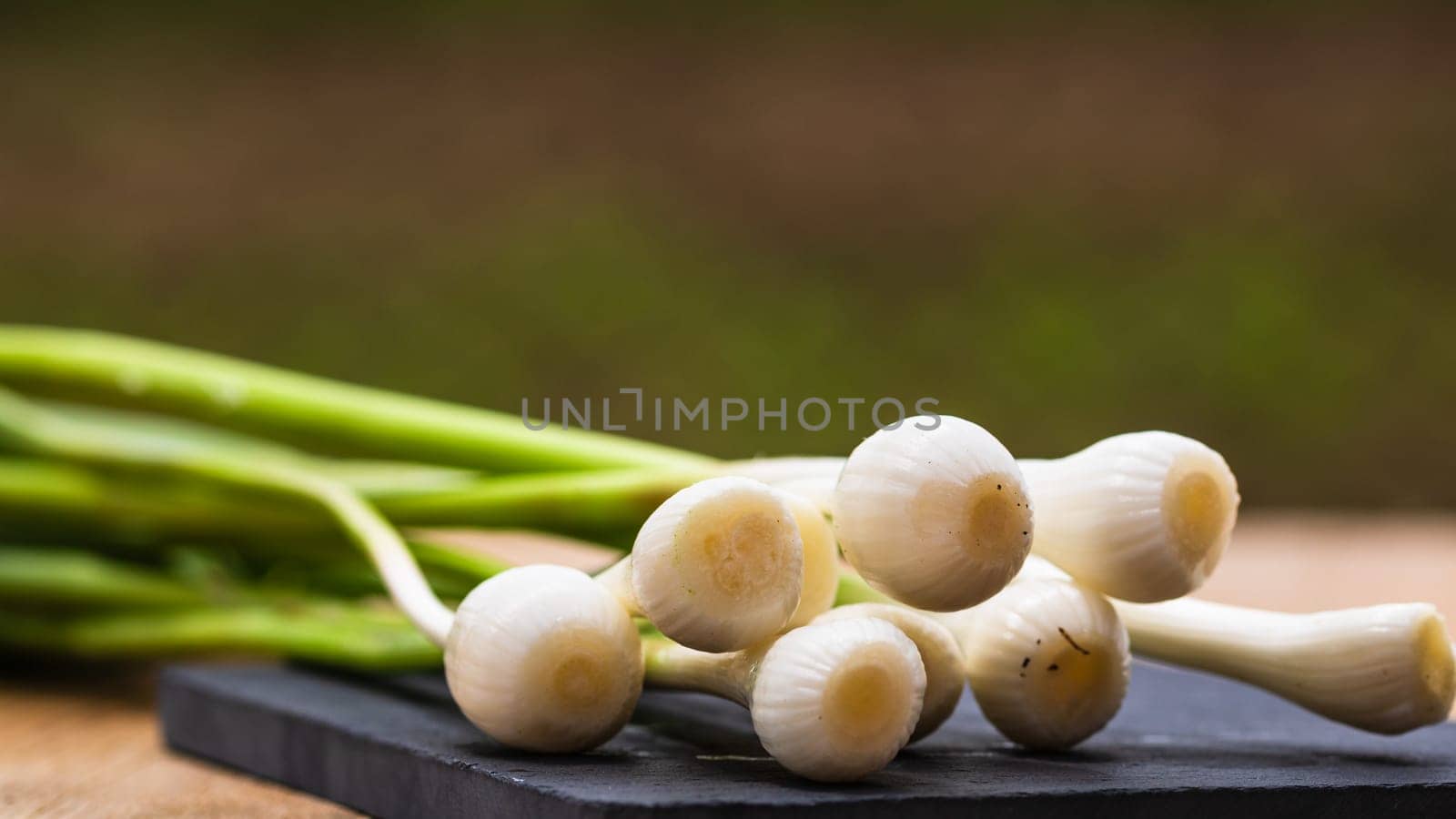 Close up of details of fresh green onions (scallion) on a cutting board isolated. by vladispas
