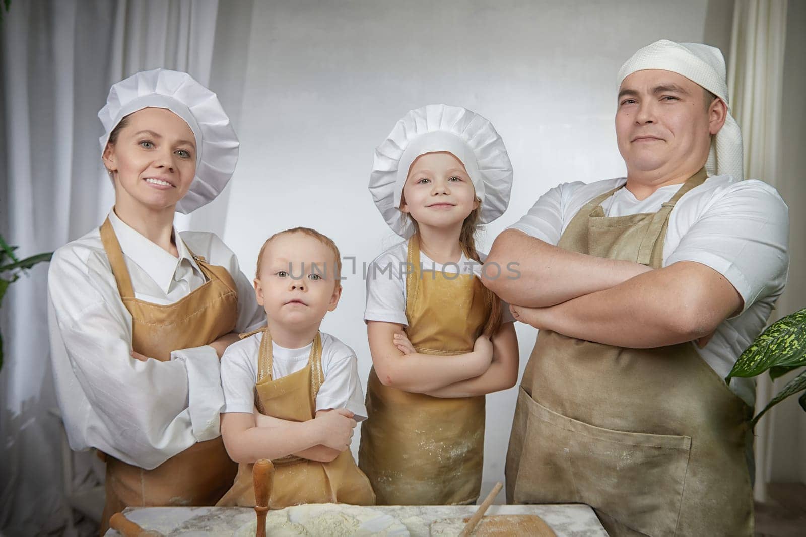 Cute oriental family with mother, father, daughter, son cooking in kitchen on Ramadan, Kurban-Bairam, Eid al-Adha. Funny family at a cook photo shoot. Pancakes, pastries, Maslenitsa, Easter