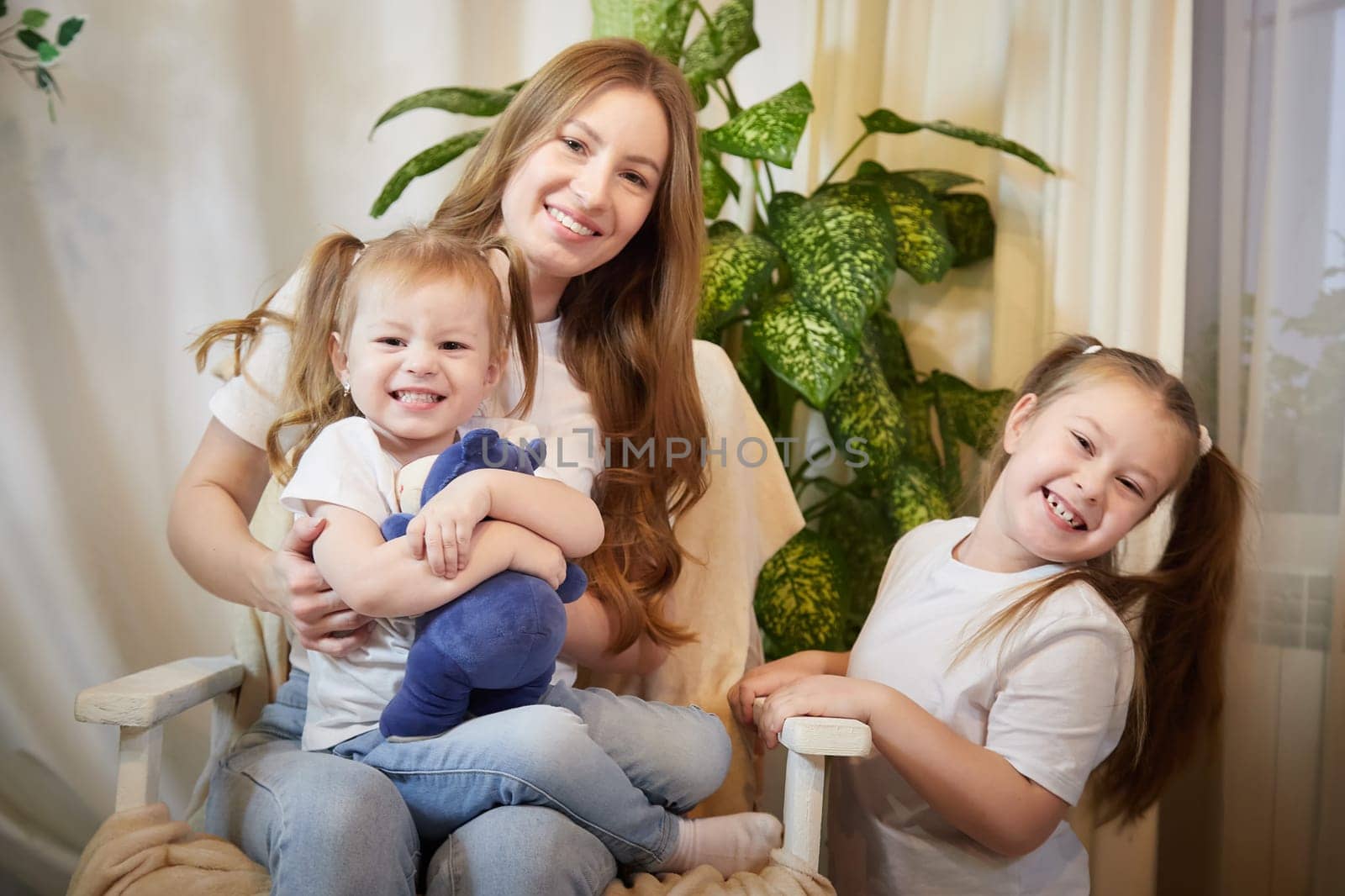 Happy family young mother babysitter relax having fun with cute little children daughters in living room at home