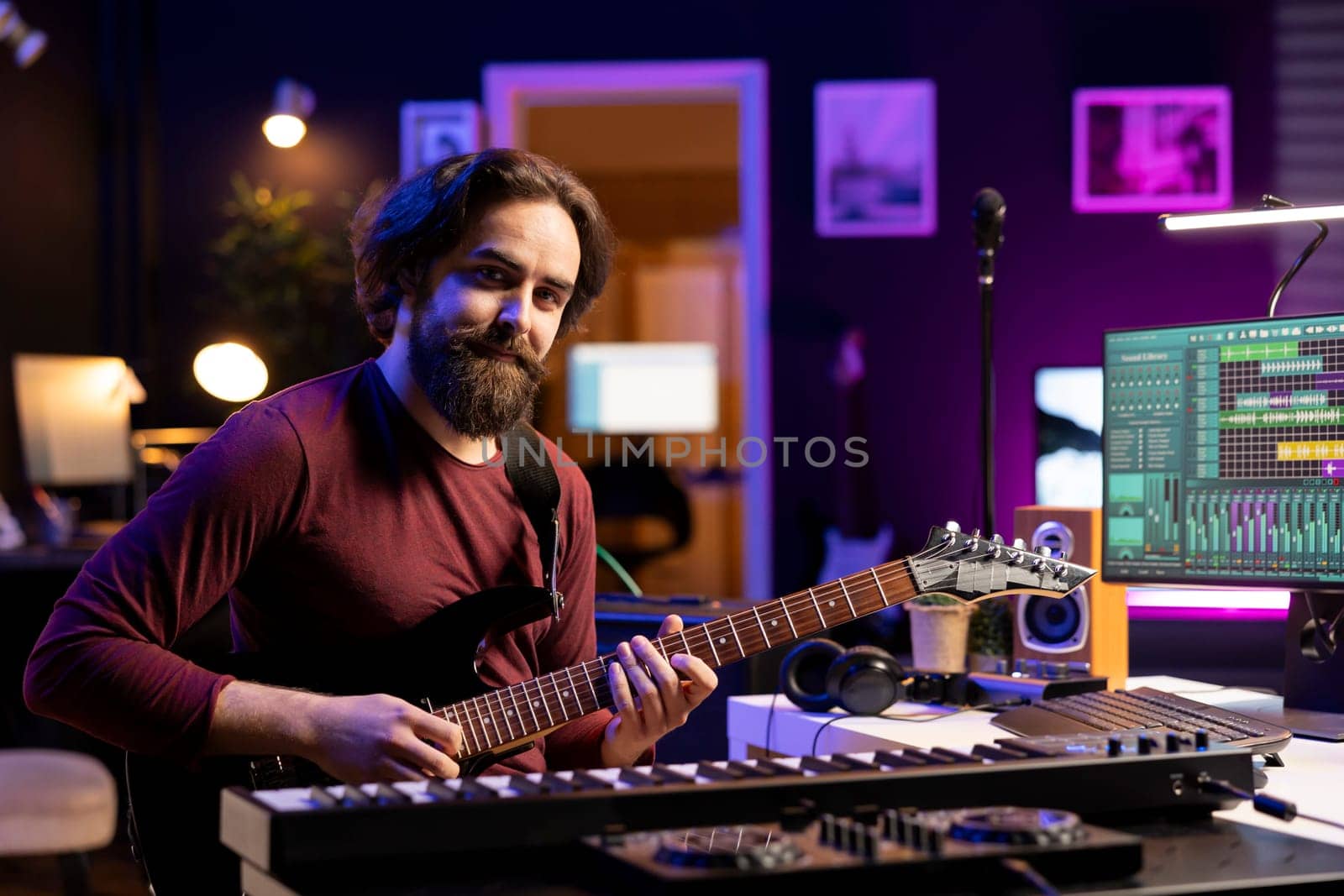 Portrait of confident artist playing acoustic guitar in his home studio, prepares for a new audio recording session to edit tracks for music industry. Songwriter guitarist composing songs.