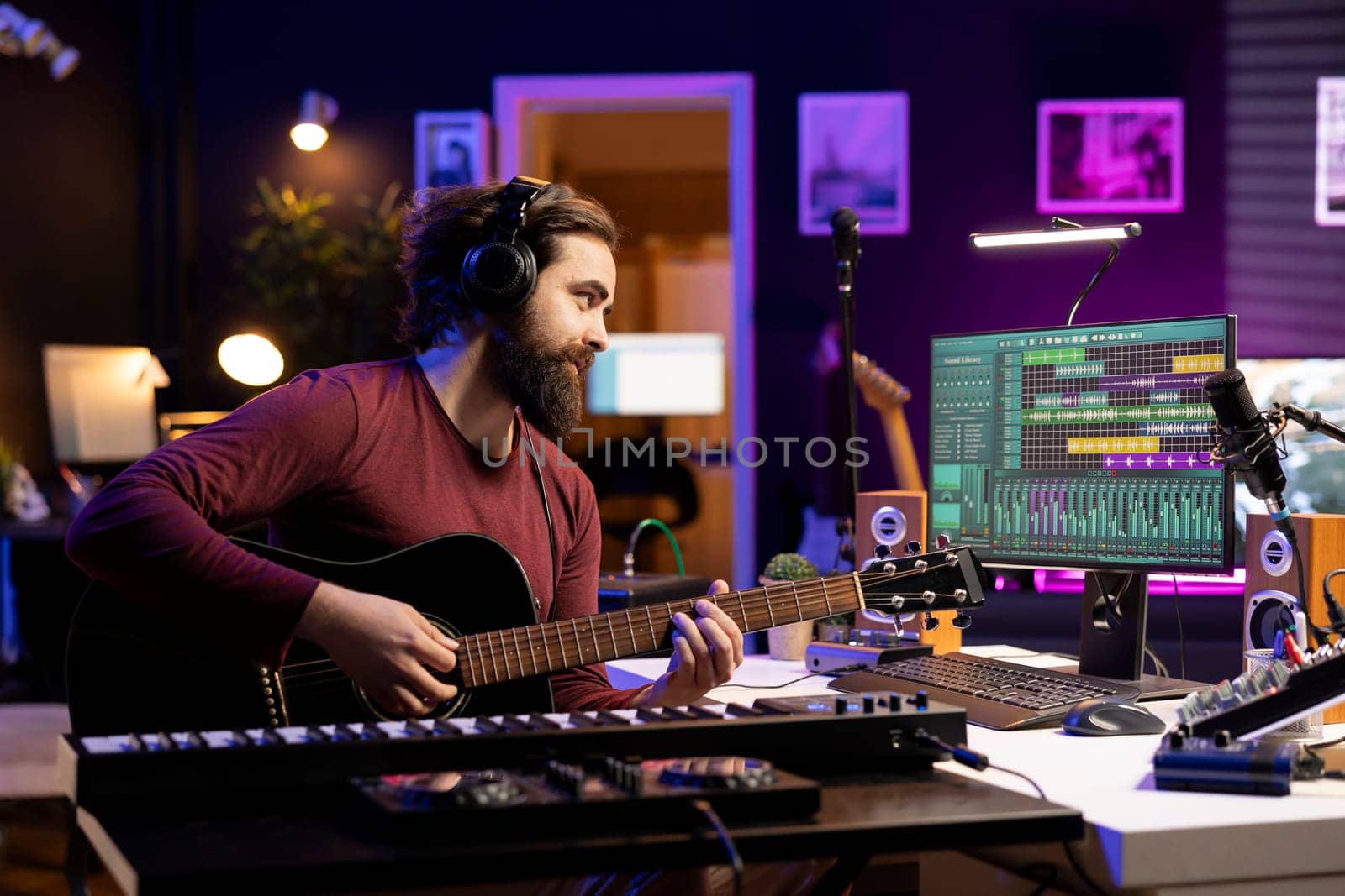 Music engineer playing new tunes on acoustic guitar and recording with daw software interface, preparing to do mixing and mastering session. Young songwriter creating soundtracks with instrument.