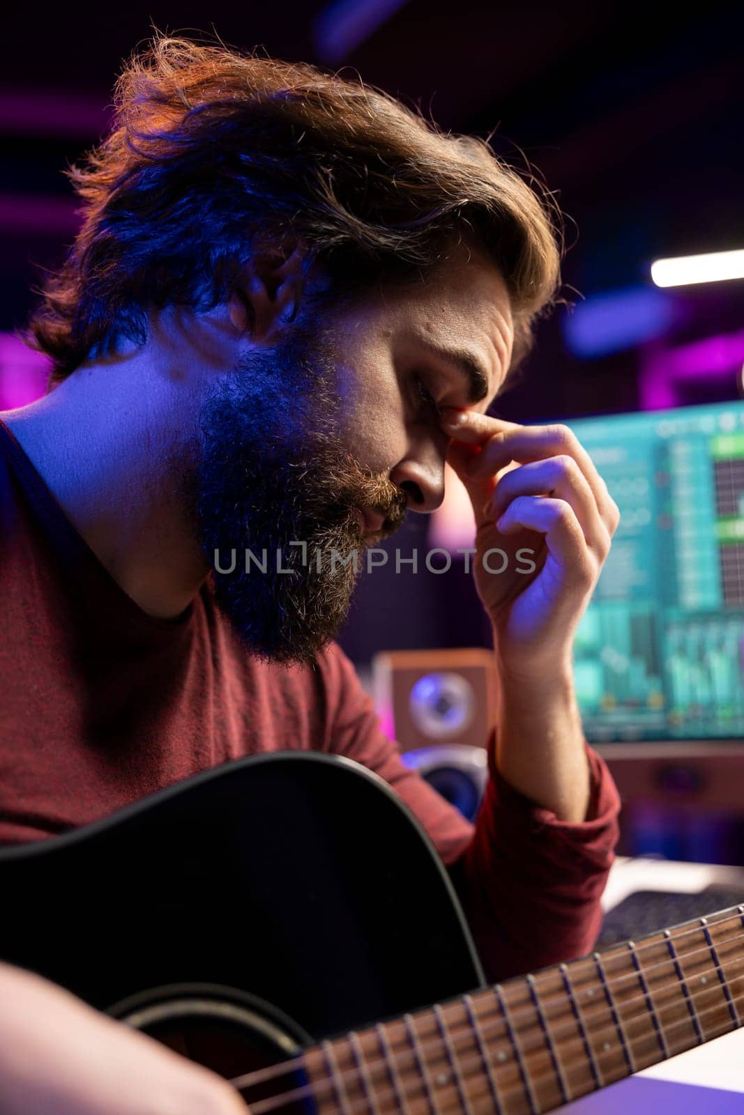 Stressed sleepy artist practicing acoustic instrument in his home studio by DCStudio