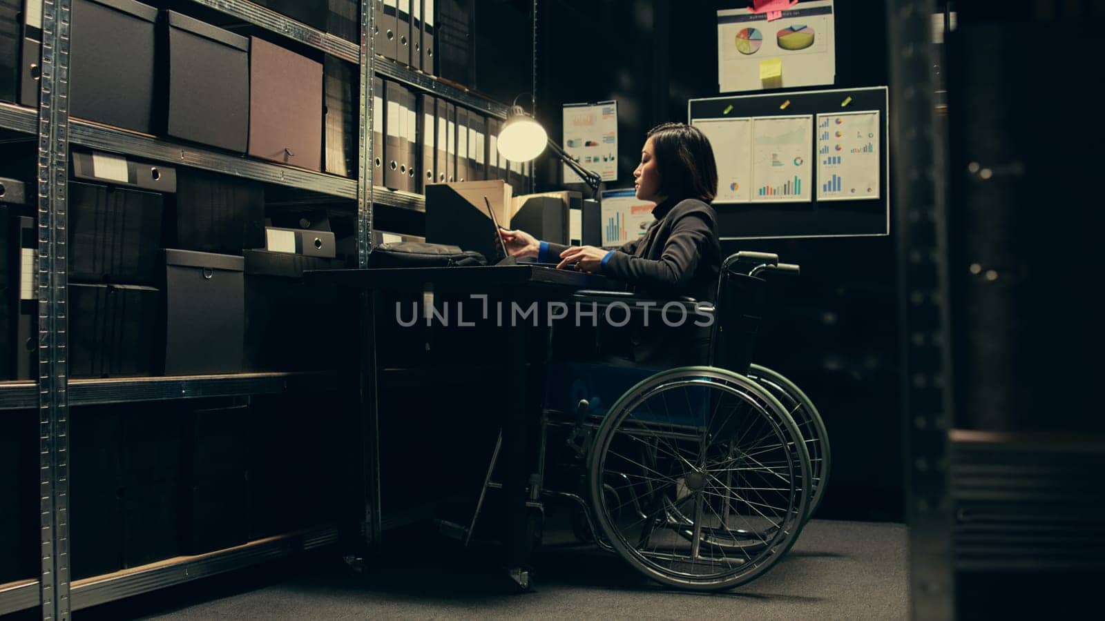 Wheelchair user conducting private investigation in disability friendly incident room, examining old cases to find connections. Detectives gathering legal information for identification. Camera B.