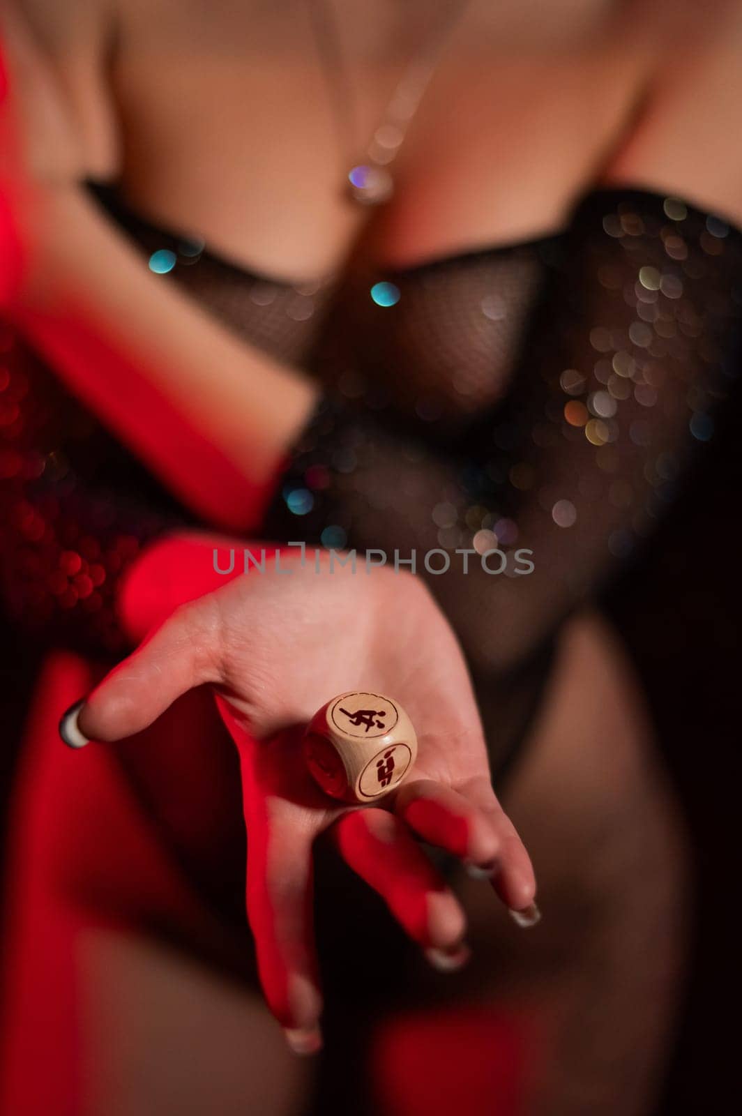 Seductive woman dressed in erotic fishnet holding dice with sex positions. Vertical photo