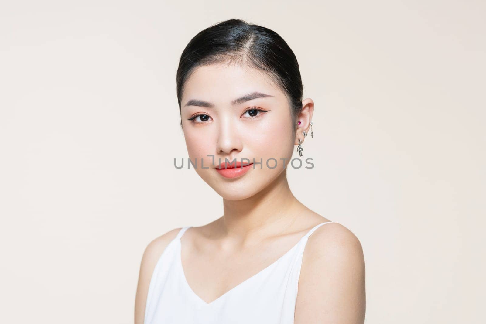 Beautiful young Asian woman with clean fresh skin on beige background