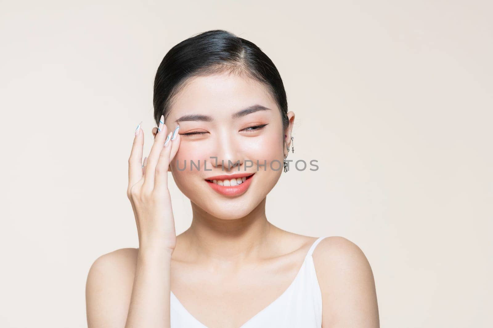 Beautiful young asian woman with clean fresh skin on beige background,