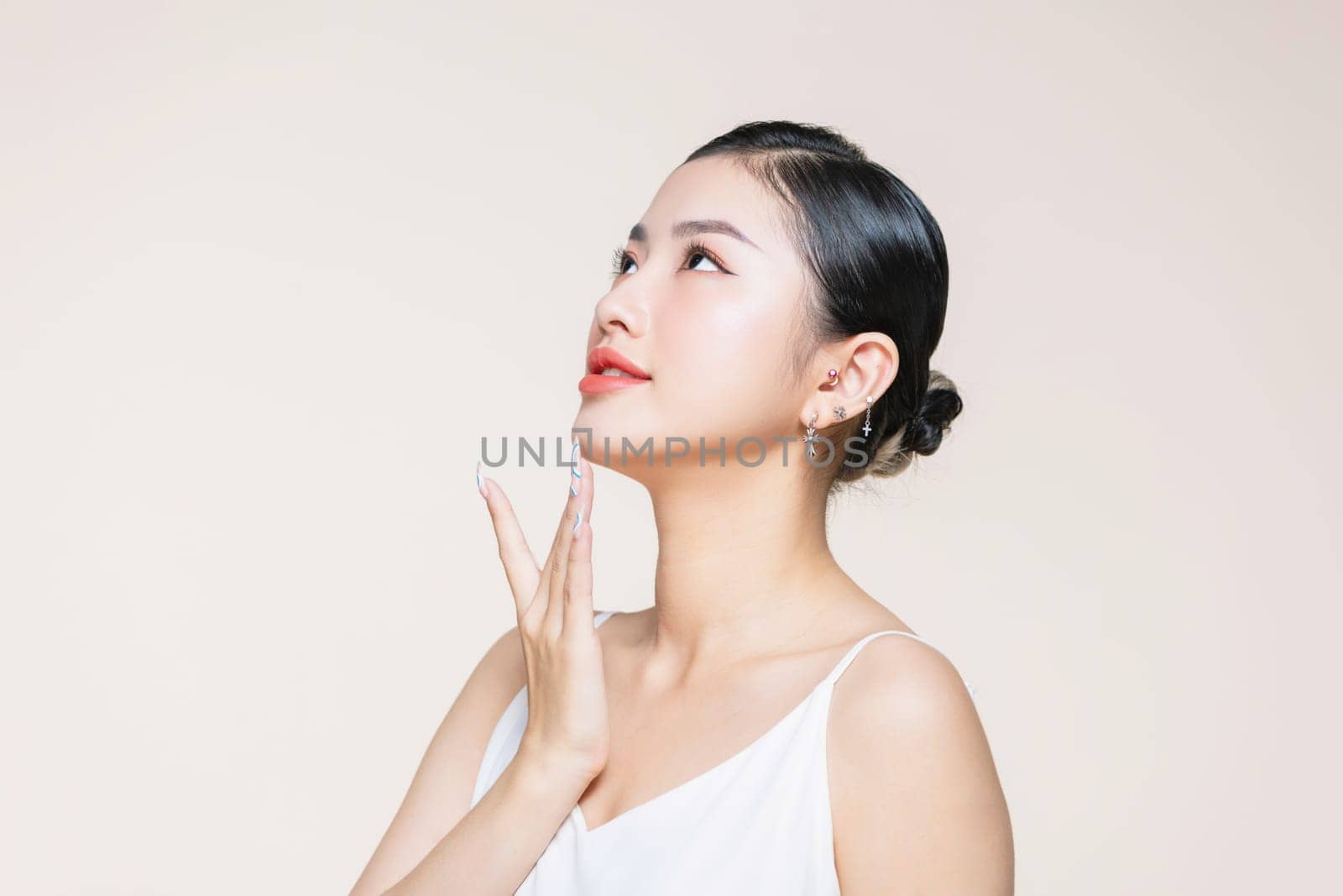 The beautiful Asian woman showing clear skin on the beige background.