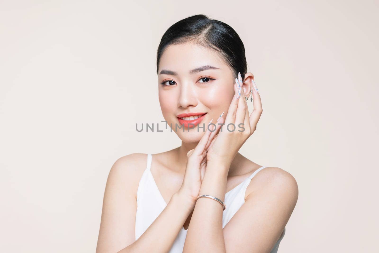 Beautiful woman face studio on beige touching face hand