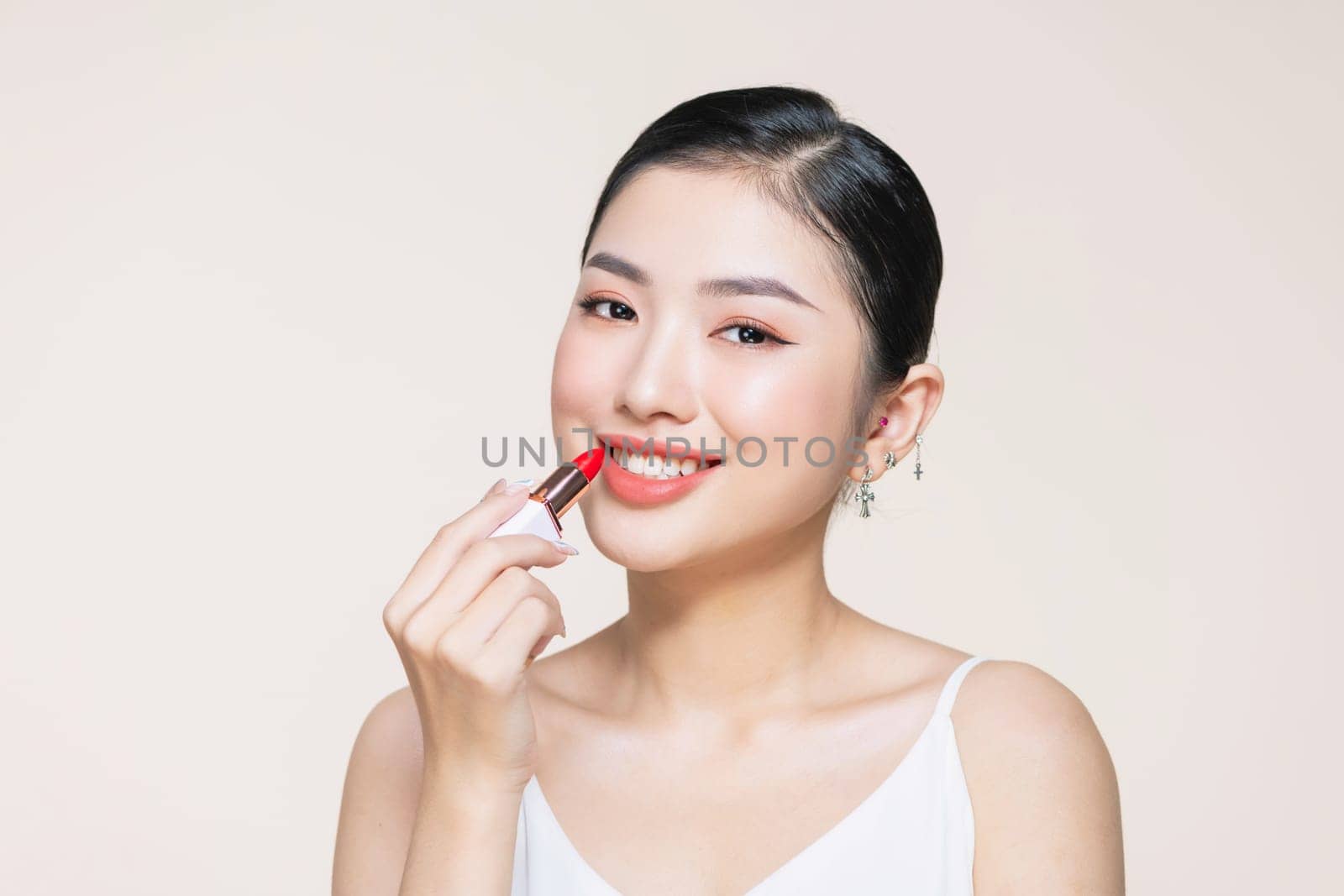 Beautiful young woman applying lipstick