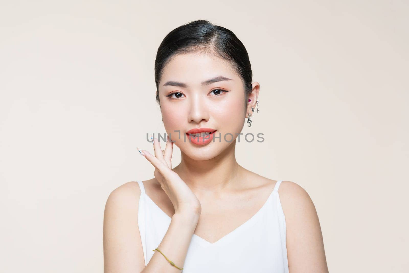 Beauty portrait of asian smiling laughing woman clean fresh face isolated on beige background