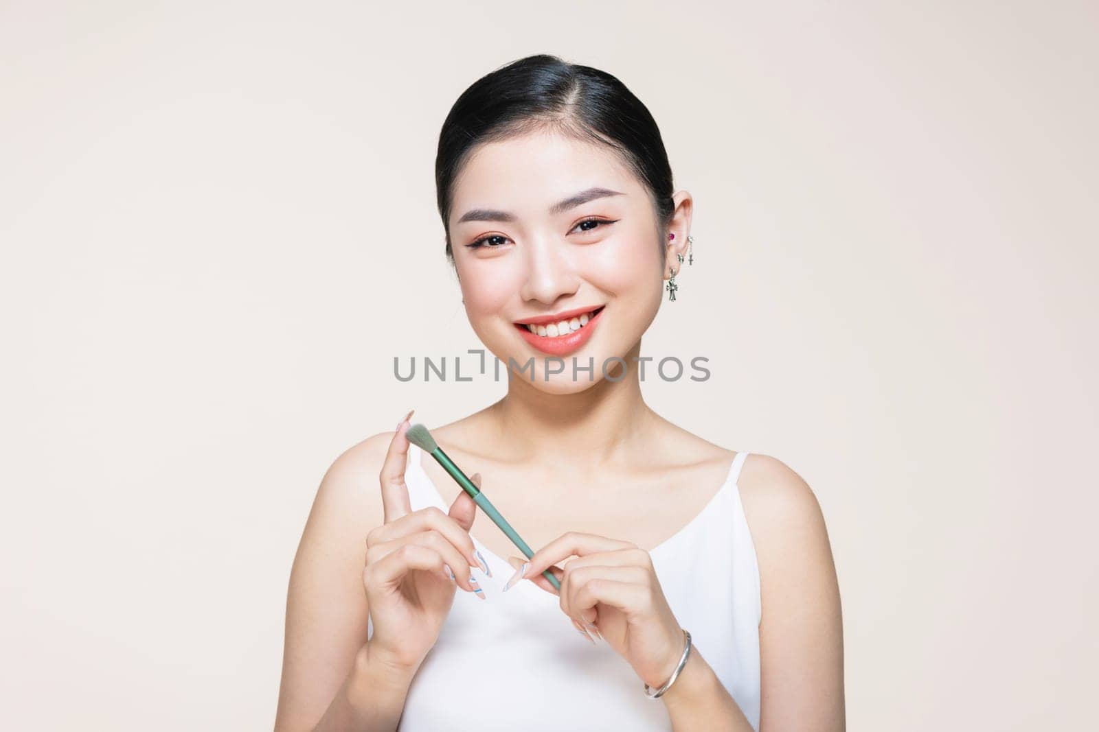 Beautiful and charming asian female applying a beautiful eyeshadow on her eyelid.