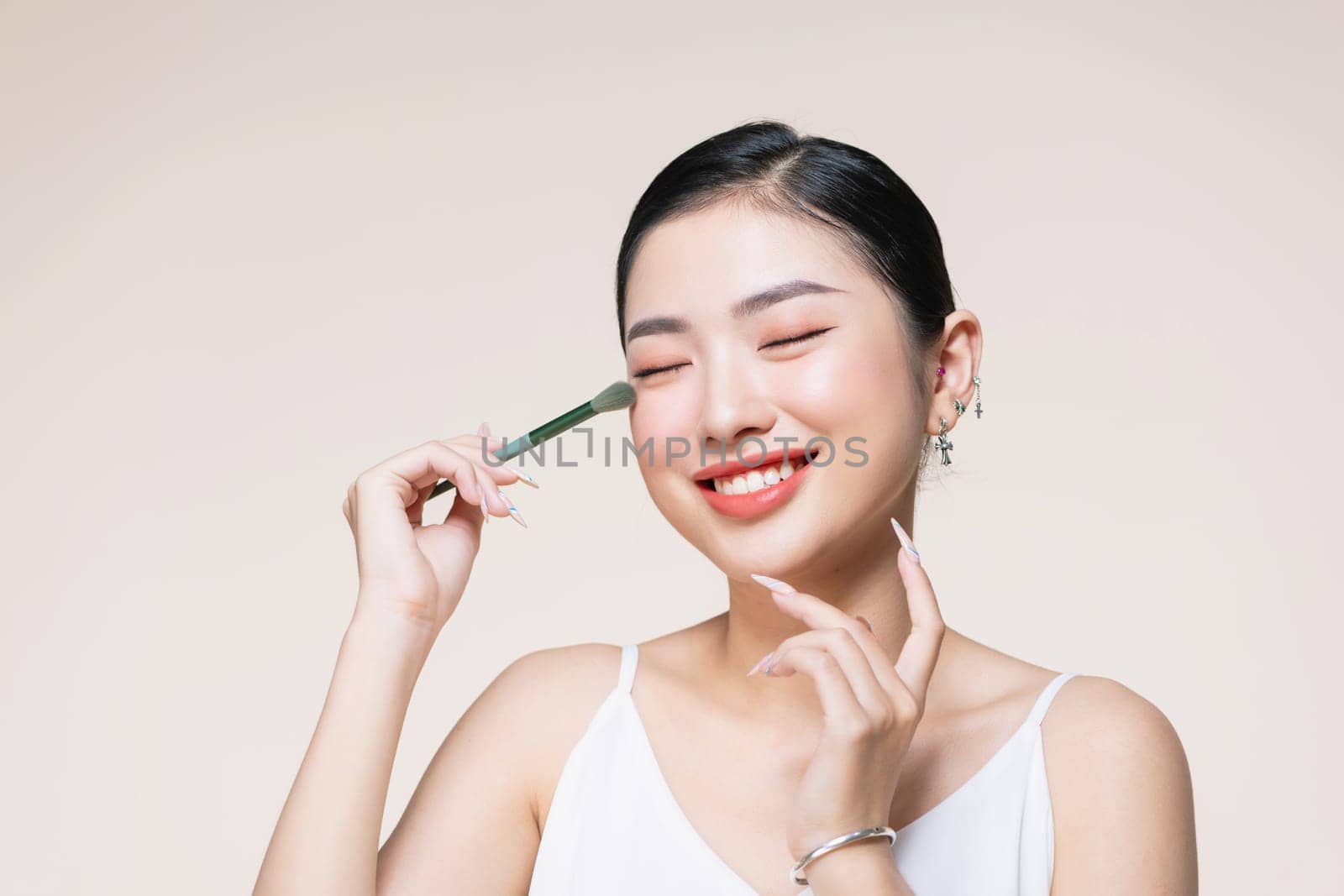 Beautiful and charming asian female applying a beautiful eyeshadow on her eyelid.
