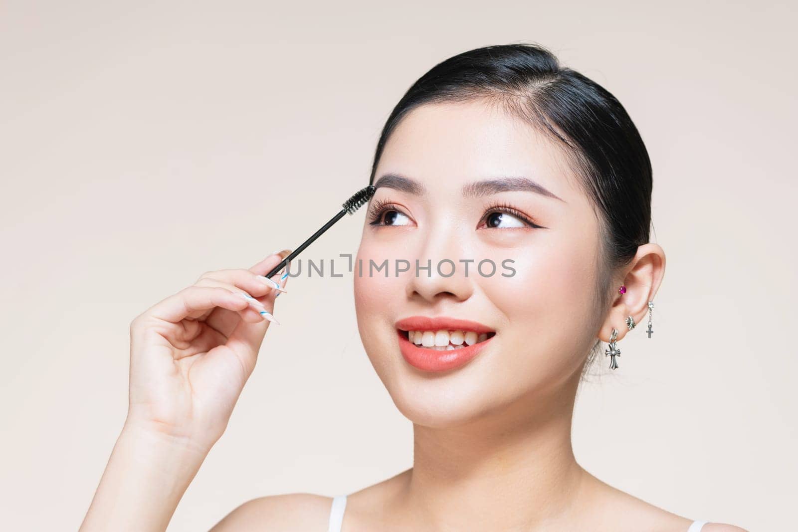 Closeup beautiful woman with eyebrow brush tool on beige