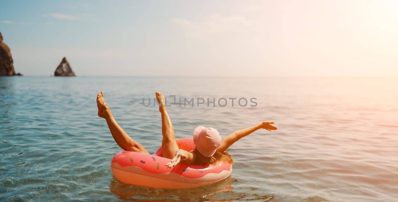 Summer vacation woman in hat floats on an inflatable donut mattress. Happy woman relaxing and enjoying family summer travel holidays travel on the sea. by Matiunina