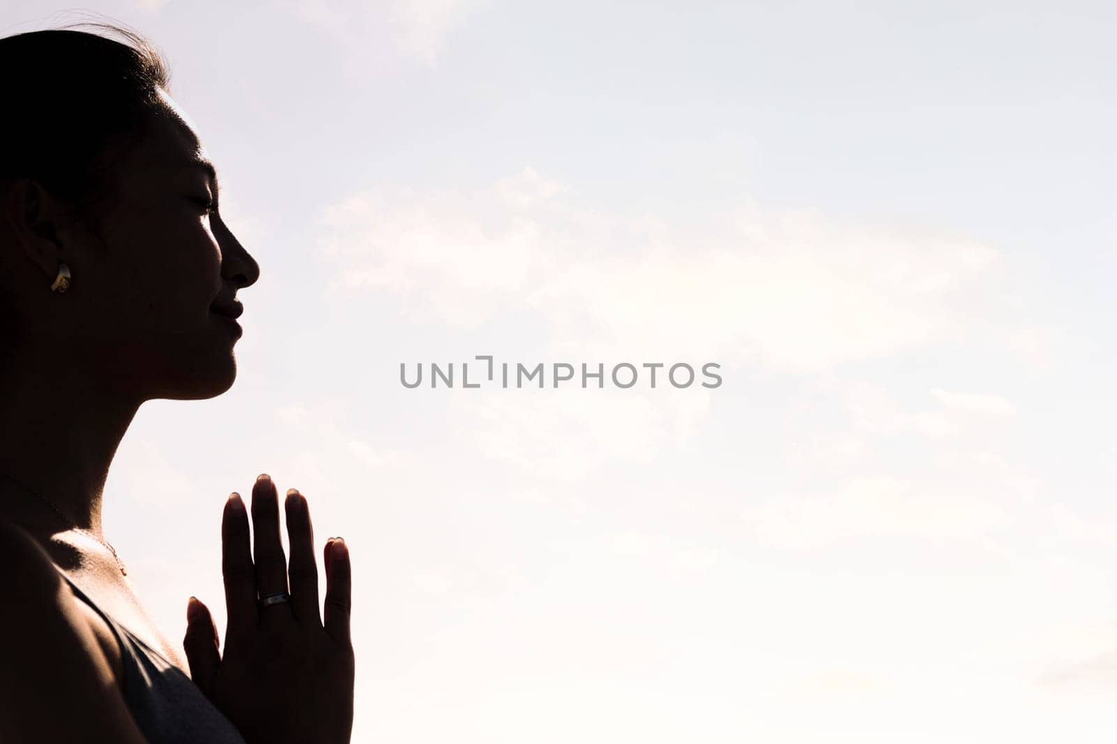 backlight portrait of young asian woman practicing yoga in pray position, concept of mental relaxation and healthy lifestyle, copy space for text