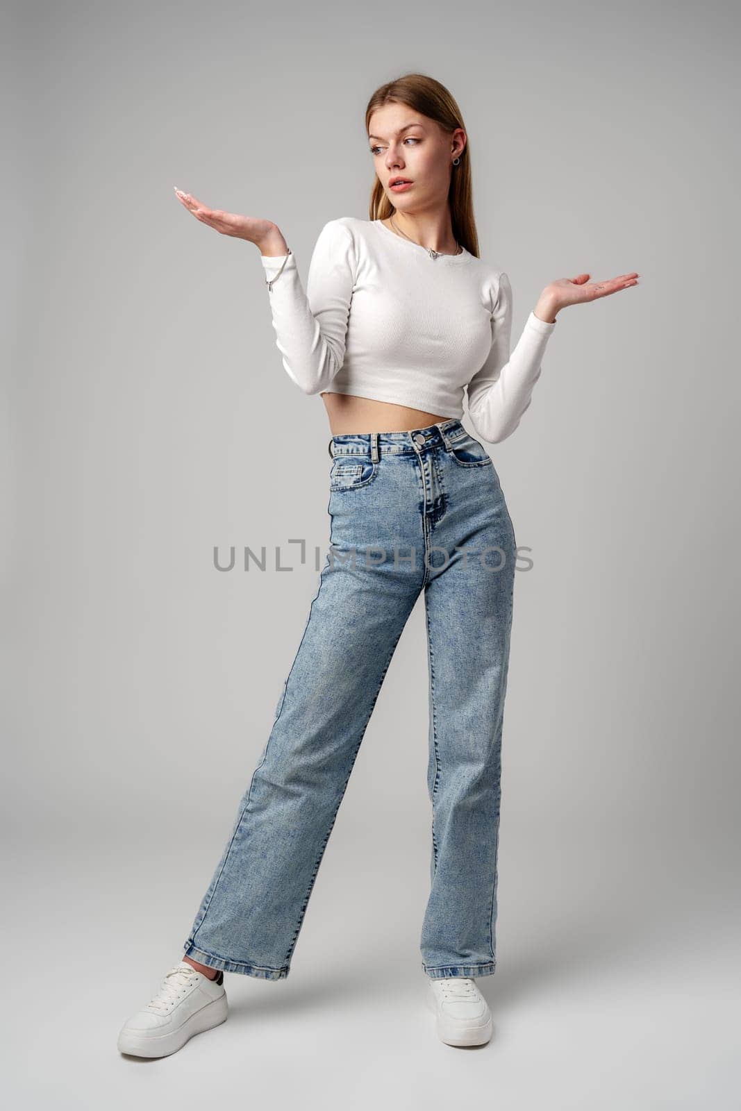 Young Woman in Blue Top Holding Out Hands in studio