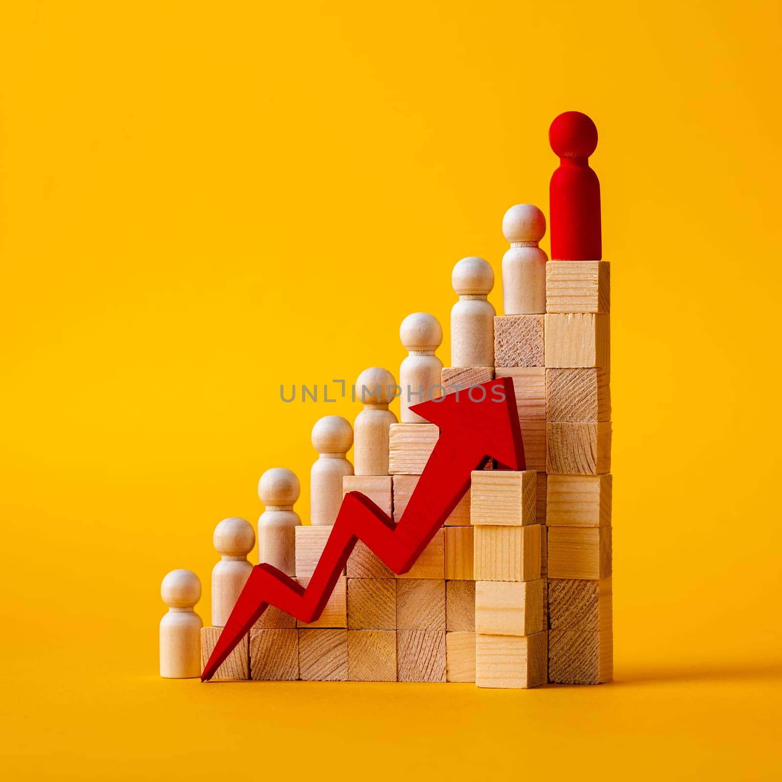 The concept of career growth. Wooden figurines stand on a ladder made wooden block on a yellow background. red arrow pointing up