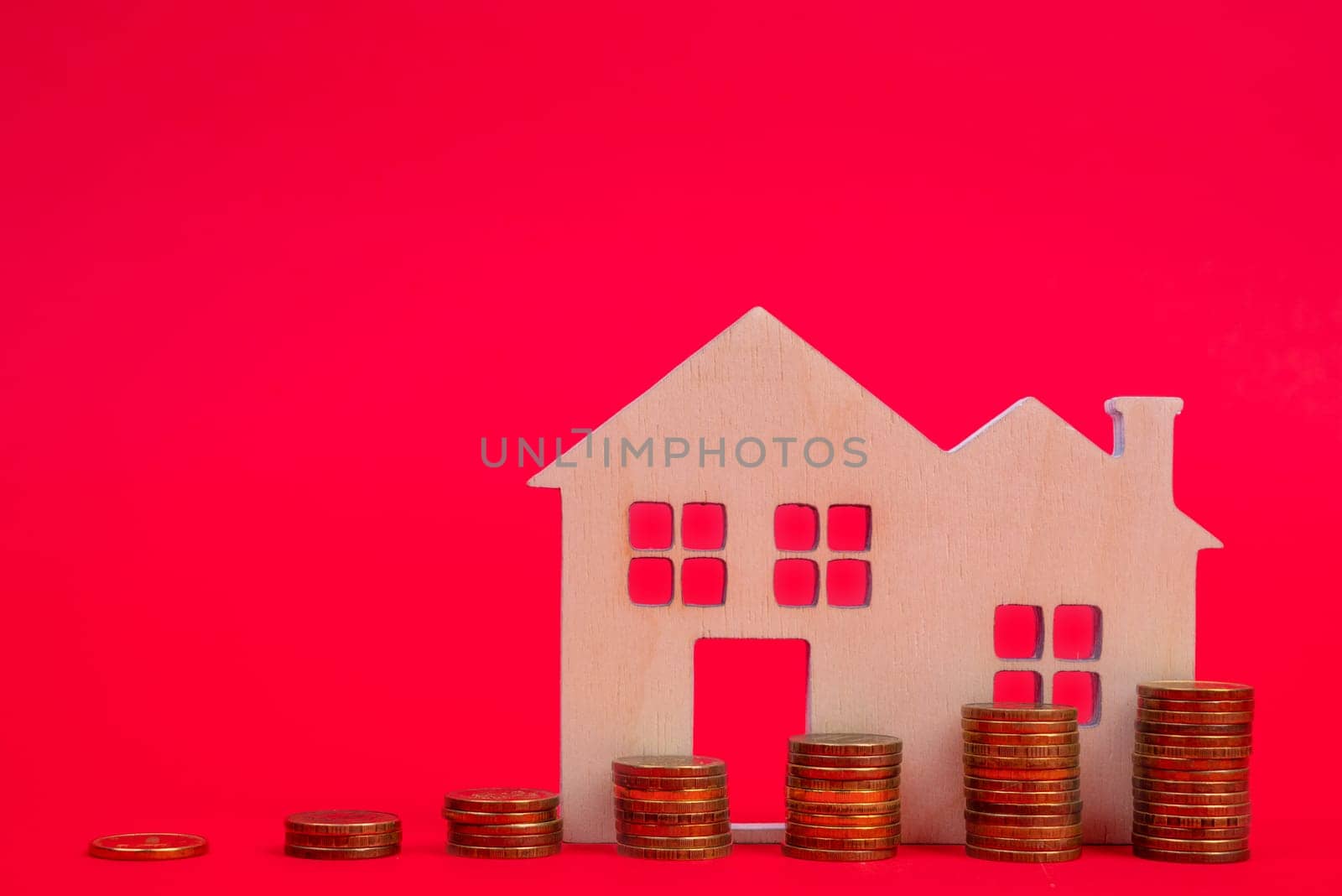 Coins and houses on a red background. The concept of the rising price of real estate