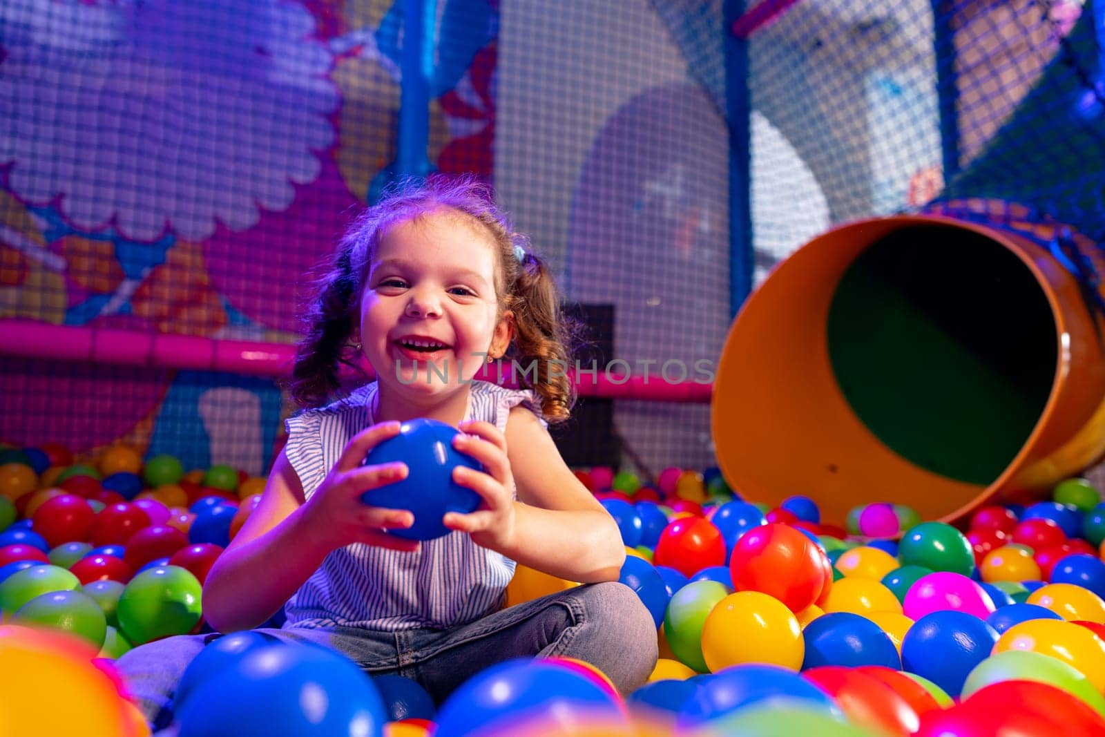 Joyful Young Girl Playing in a Colorful Ball Pit at an Indoor Playground by Fabrikasimf