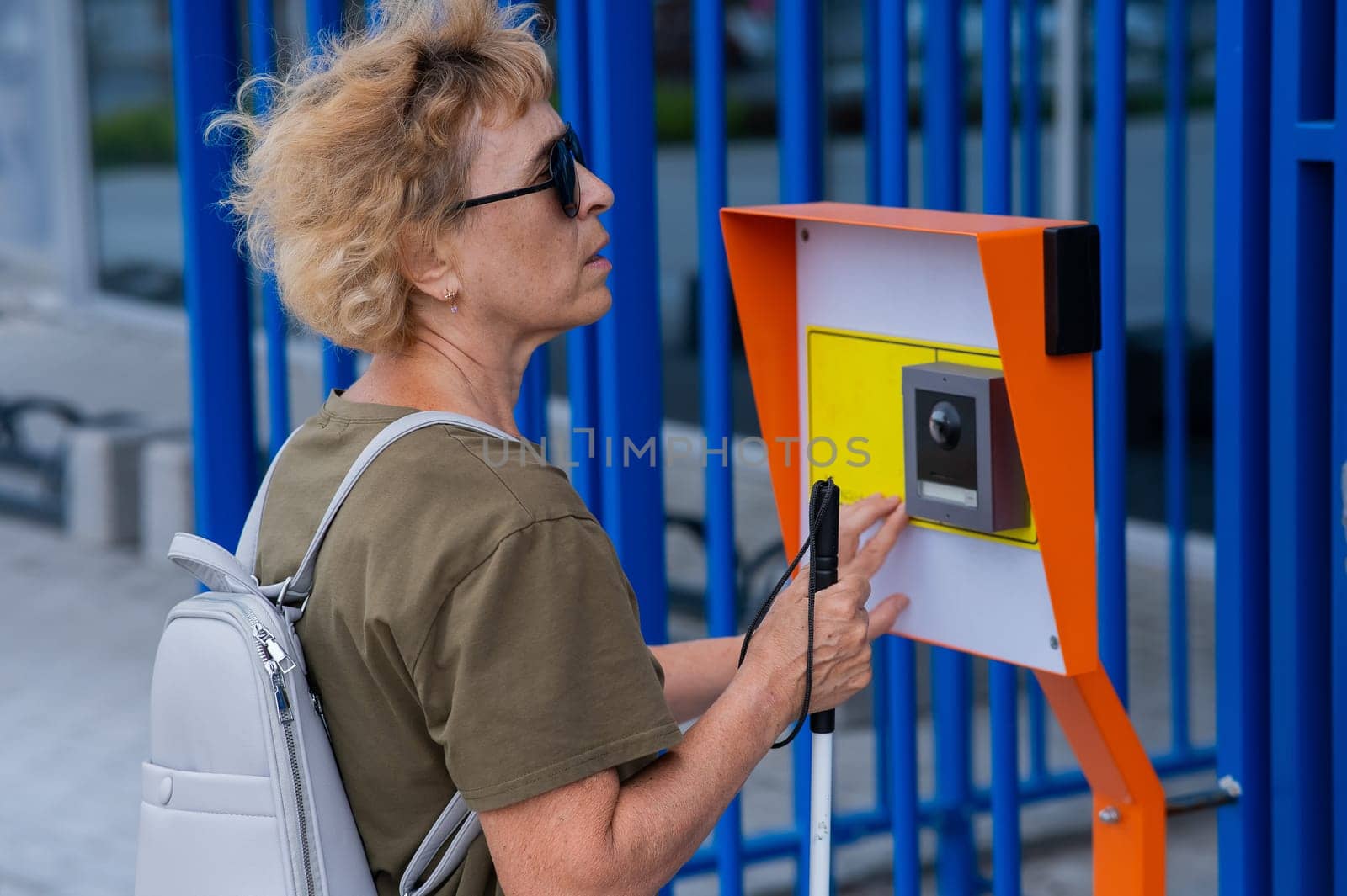 An elderly blind woman reading a text in braille. Button for calling help for people with disabilities