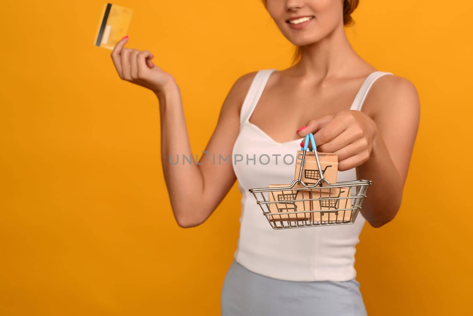 Close up of female hand horizontal holds toy metal shopping basket with blue plastic handle isolated on background. by zartarn