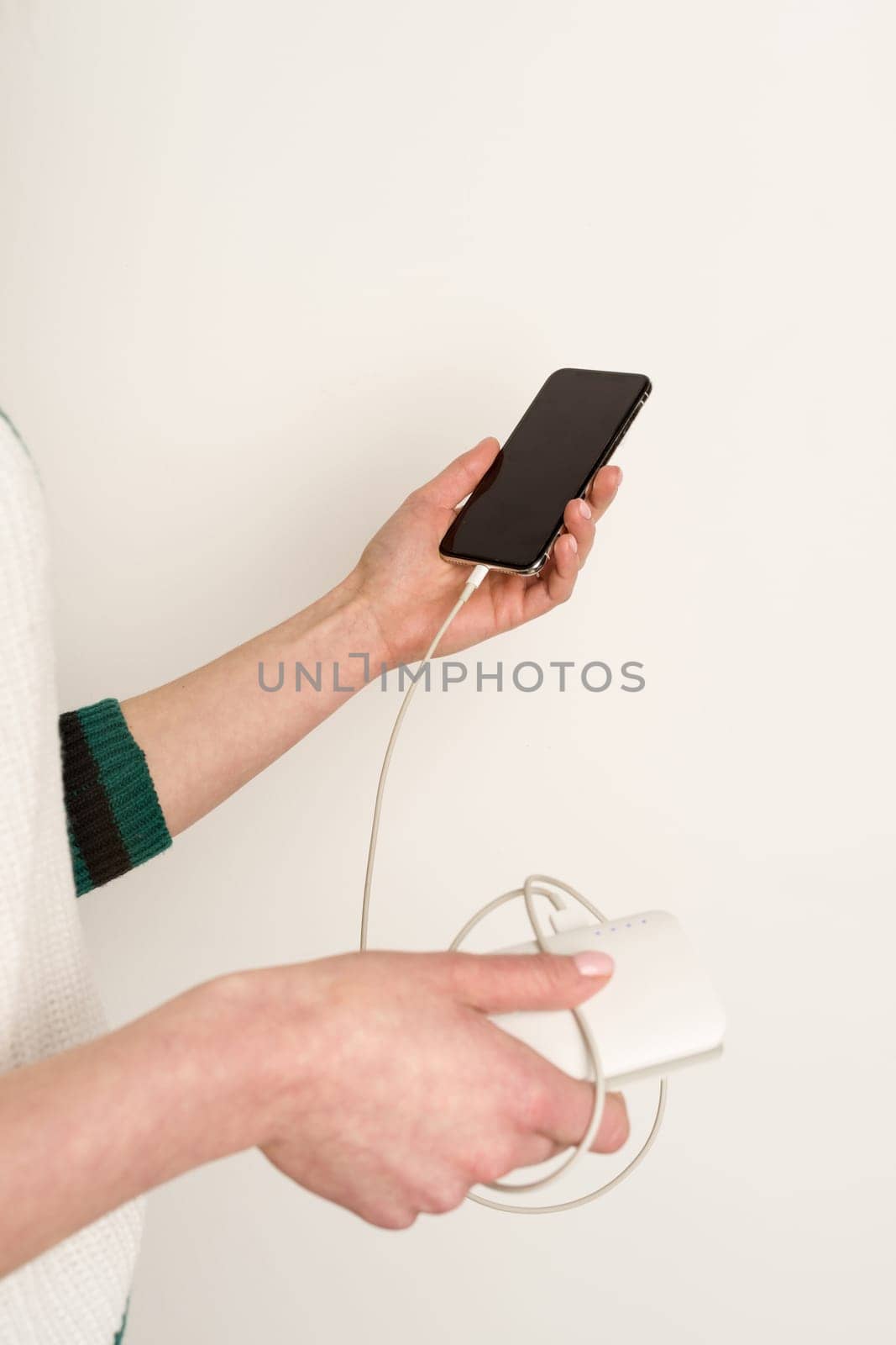 emale hands holding and using smartphone while charging power bank - image
