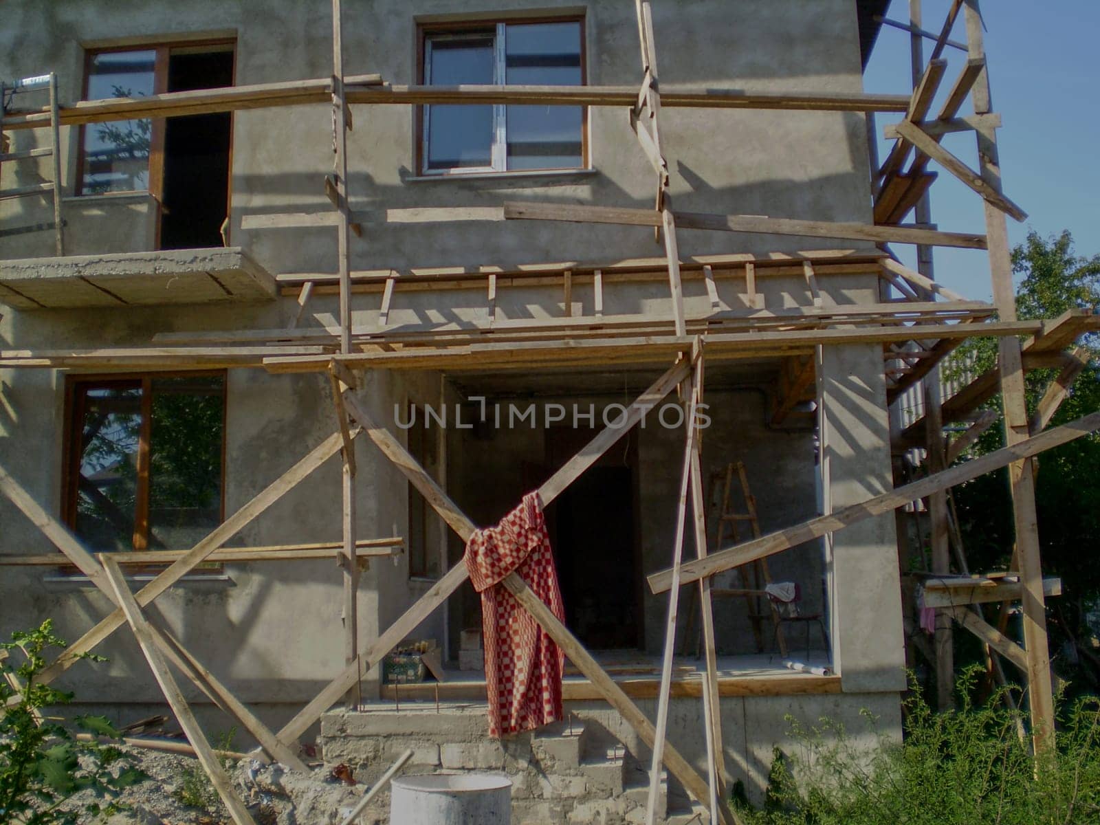 A two-story house fenced with wooden scaffolding.