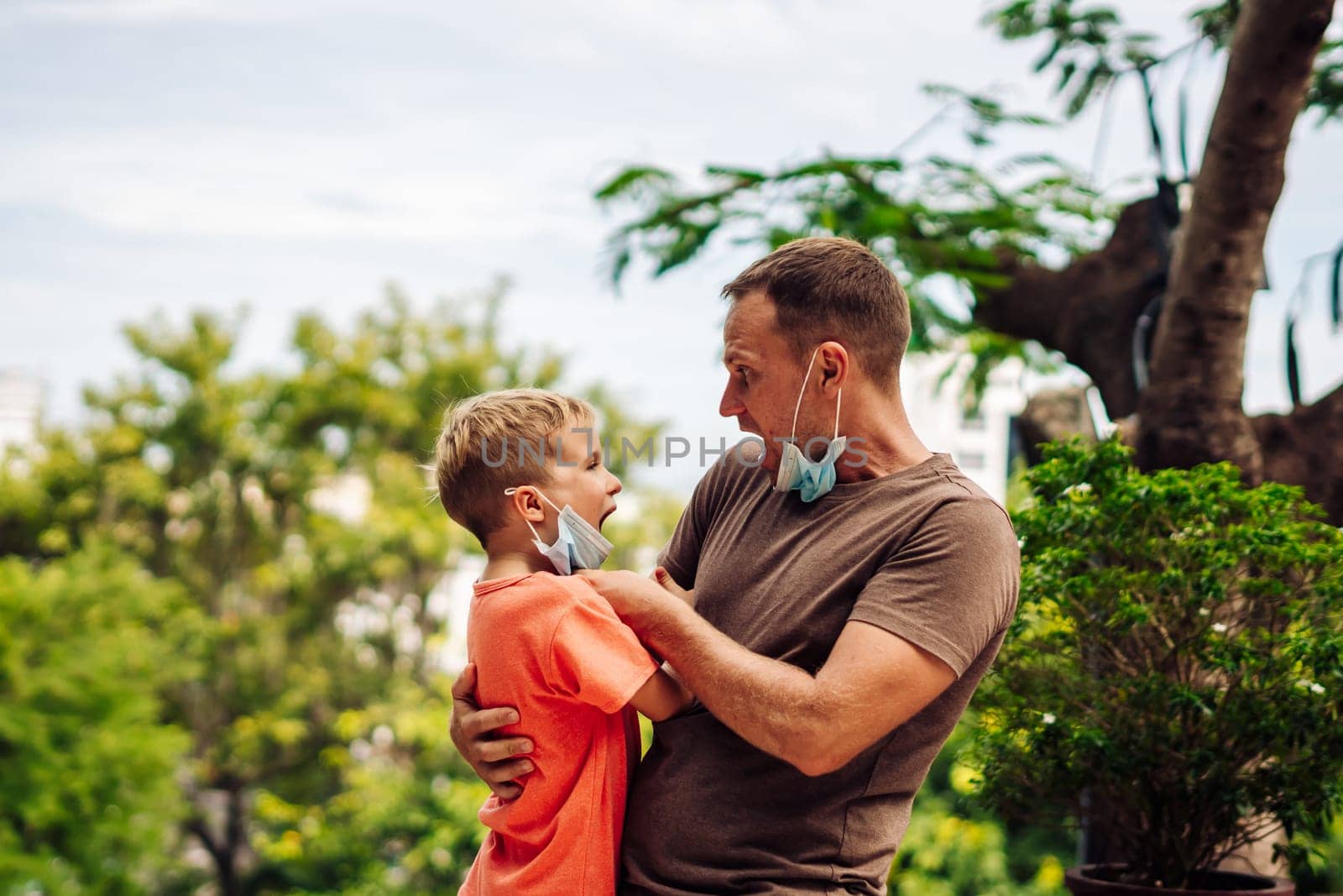 Father and little son hugging, making faces, show a tongue, open mouth, funny plays. Happy childhood.