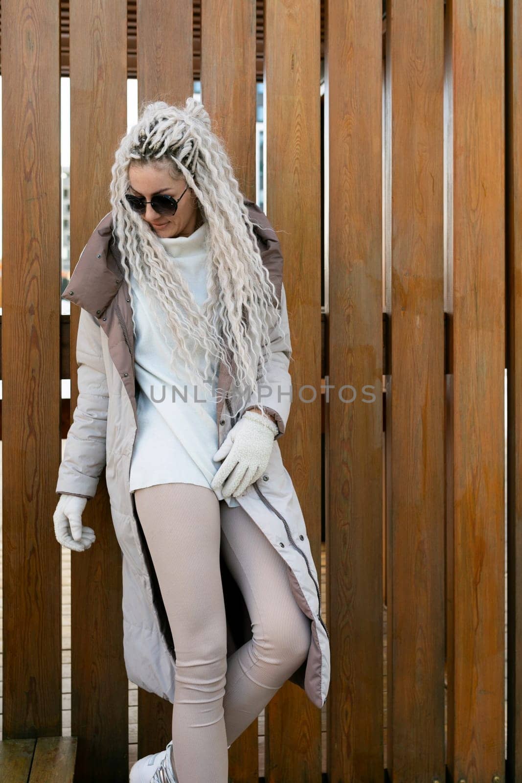 A woman with long white hair is standing while wearing a luxurious fur coat. The womans hair cascades down her back as she elegantly poses in the warm winter attire.