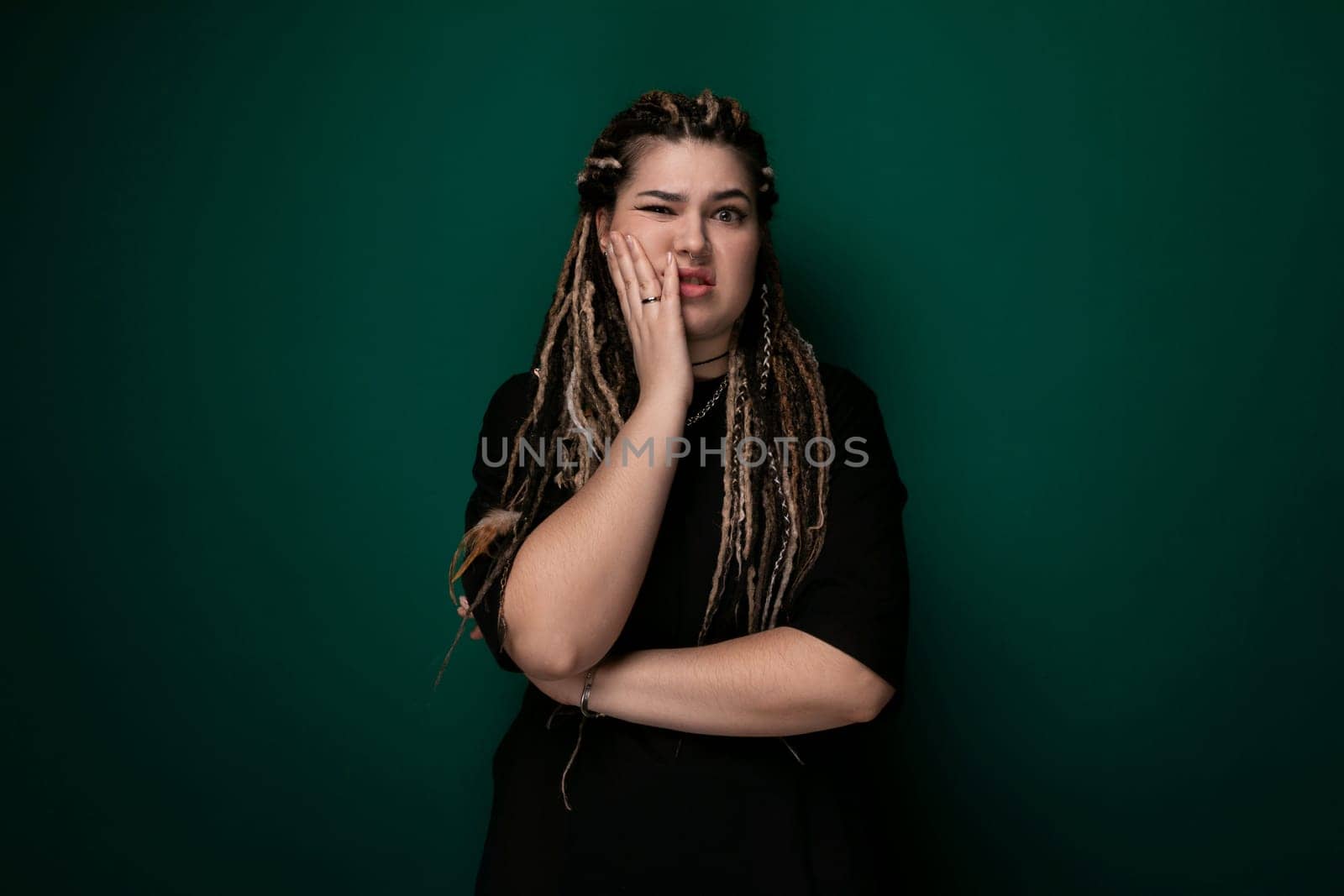A woman with long dreadlocks covering her mouth, creating a secretive and mysterious appearance. Her face is partially hidden by the tangled hair, adding an element of intrigue to the image.