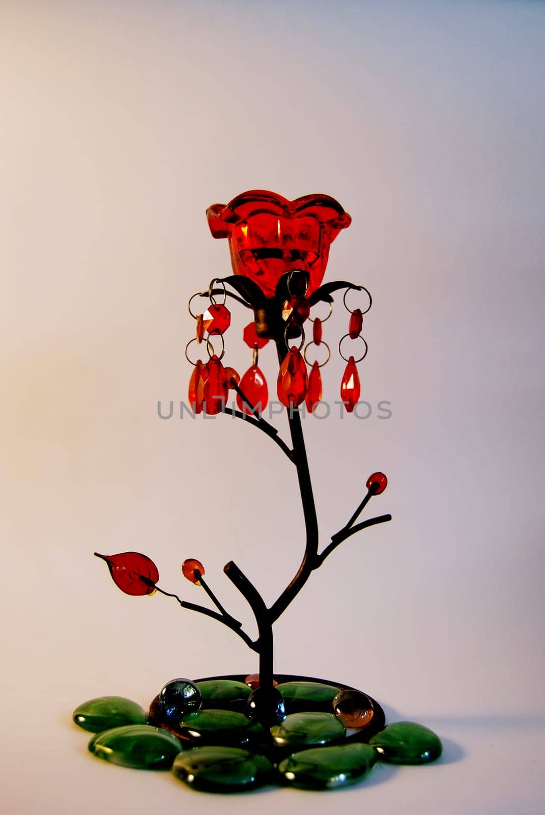 Candlestick in the shape of a flower.With a red bud and decorated with green stones.