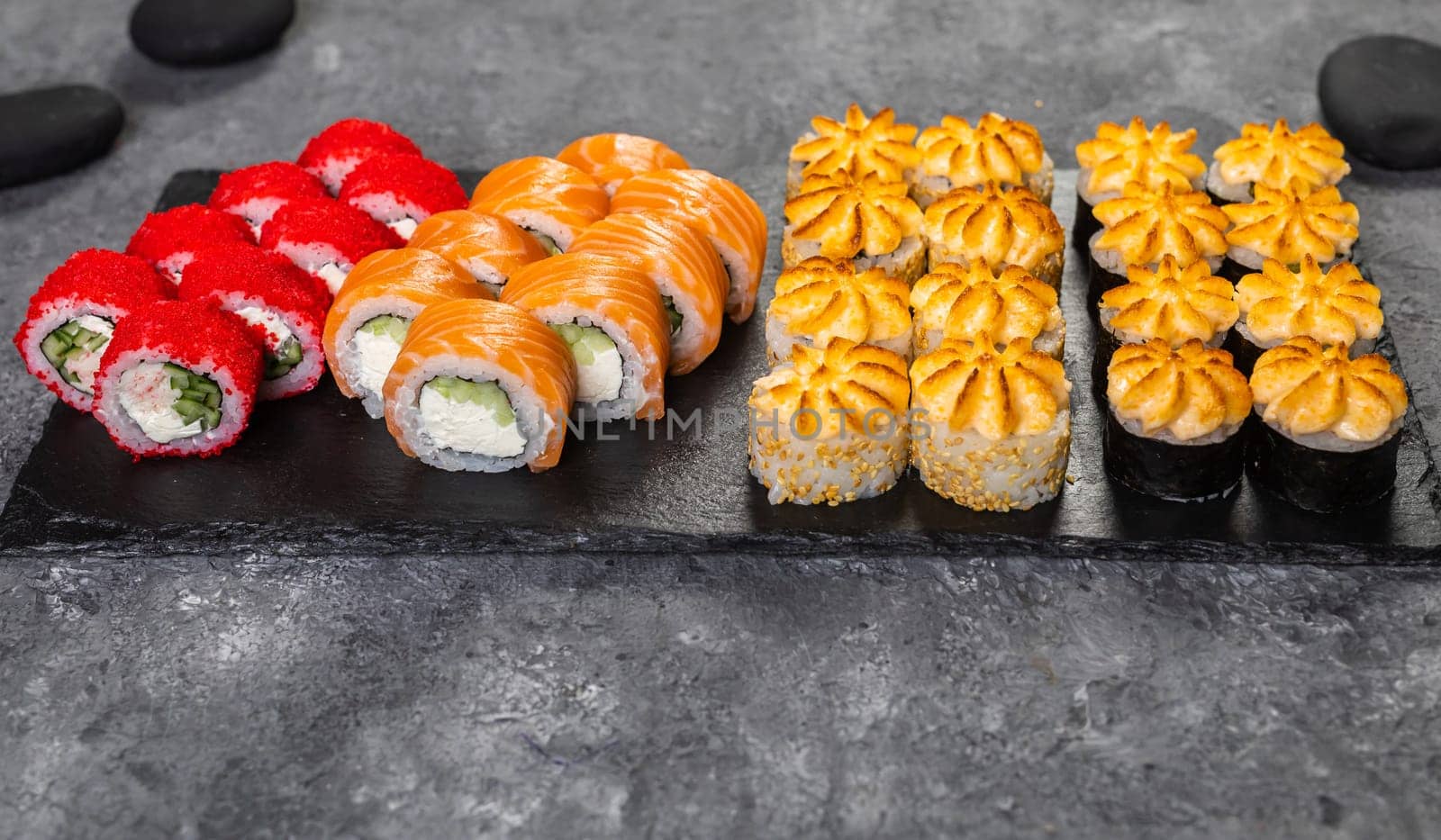 Top view sushi set. Philadelphia roll, california, unagi with fresh ingredients on black background. Sushi menu. Japanese asian food