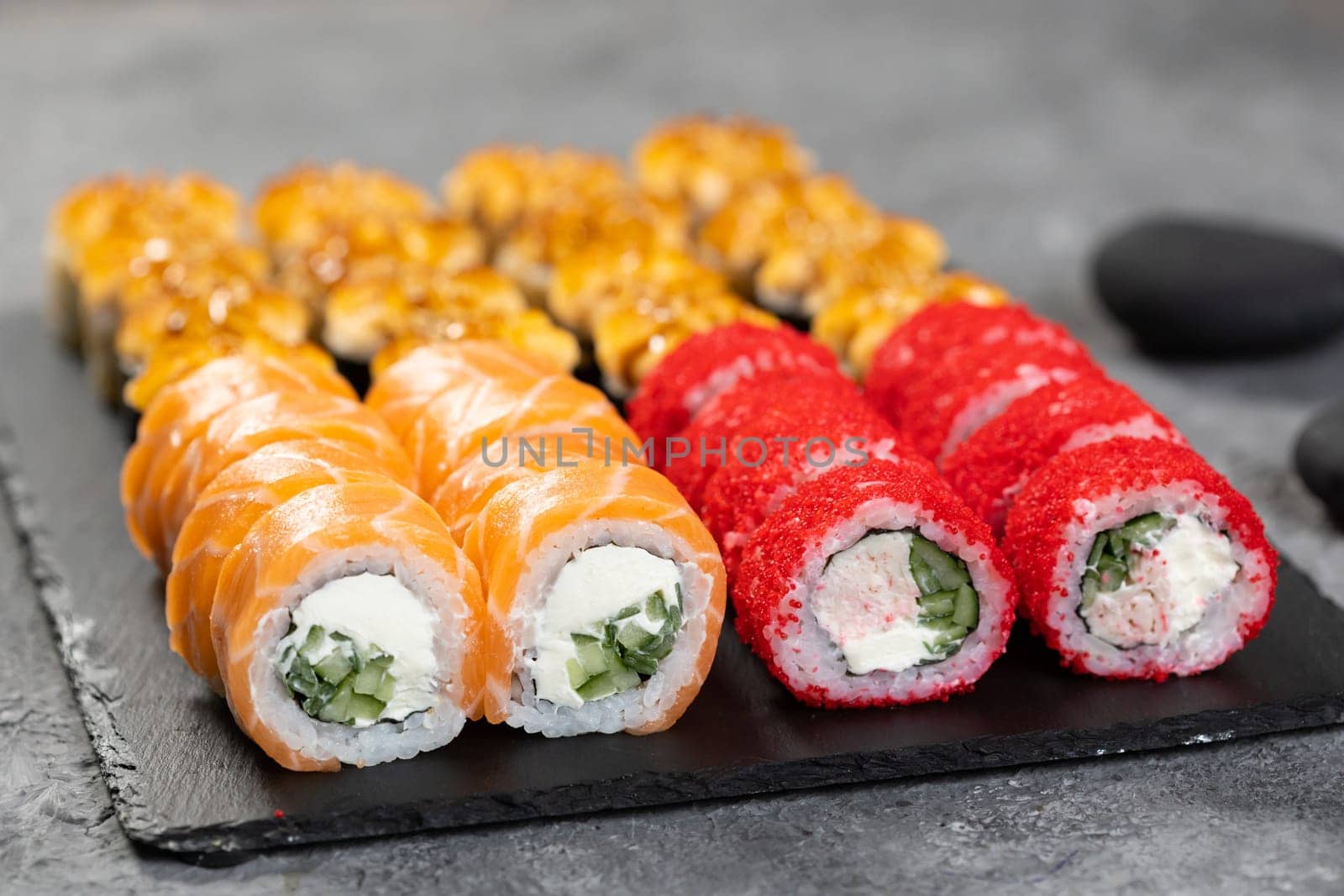 Top view sushi set. Philadelphia roll, california, unagi with fresh ingredients on black background. Sushi menu. Japanese asian food