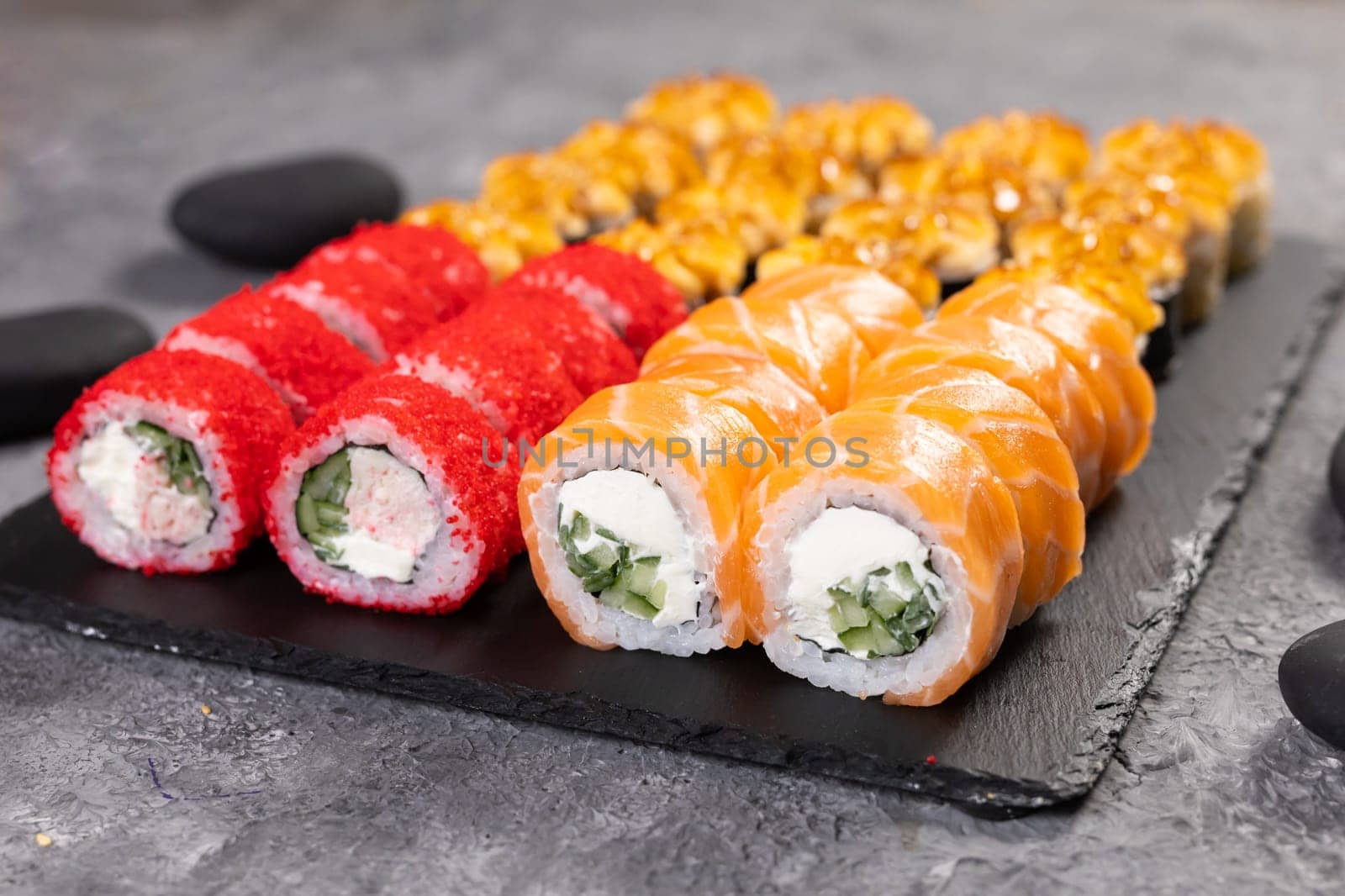 Top view sushi set. Philadelphia roll, california, unagi with fresh ingredients on black background. Sushi menu. Japanese asian food