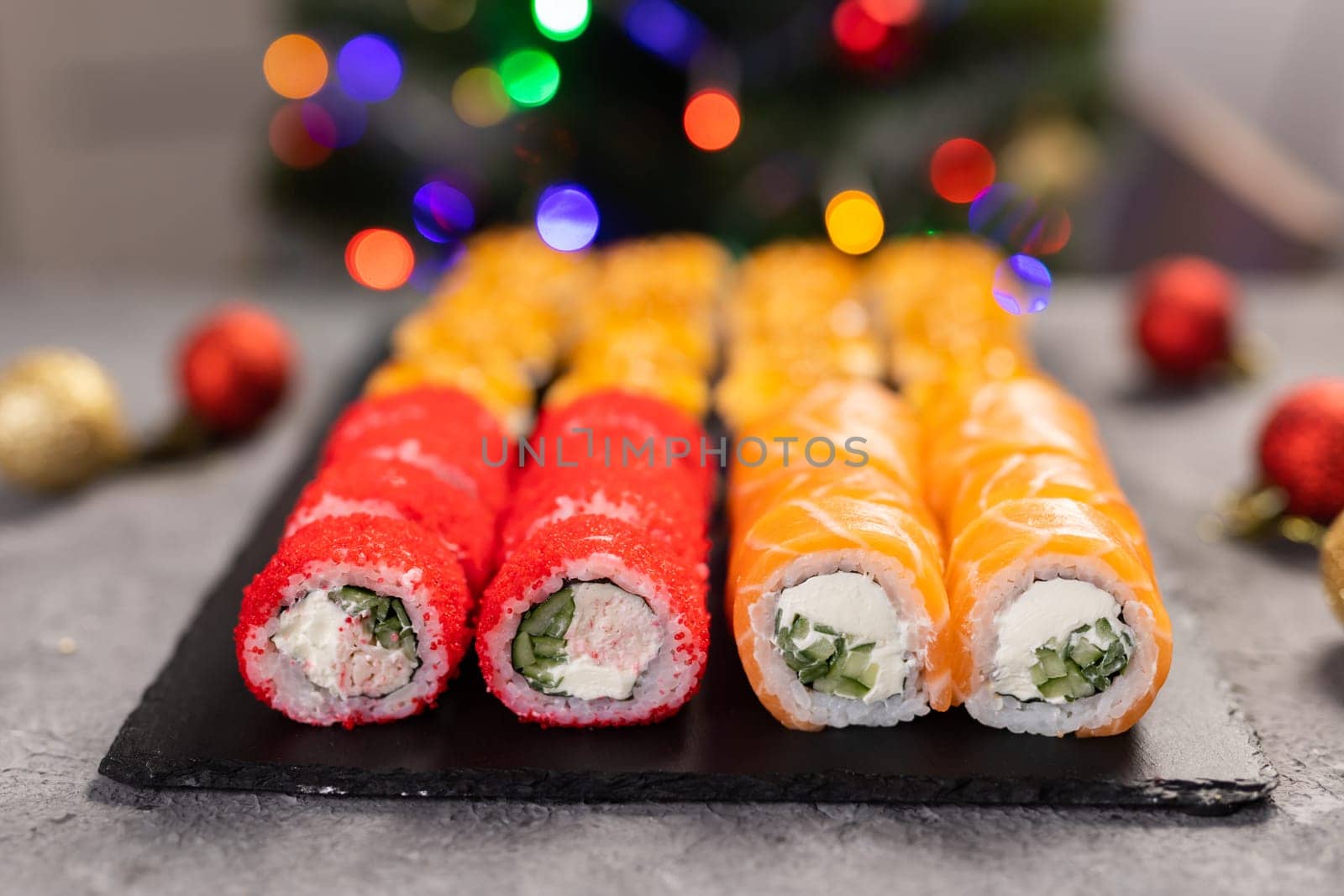 Sushi for Christmas New Year party, winter holiday food delivery menu. Sushi set asian food in background Christmas tree with festive garland