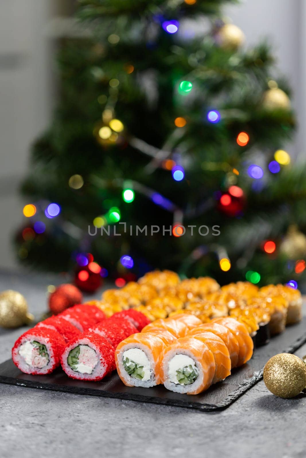 Sushi for Christmas New Year party, winter holiday food delivery menu. Sushi set asian food on background Christmas tree with festive garland copy space by Satura86