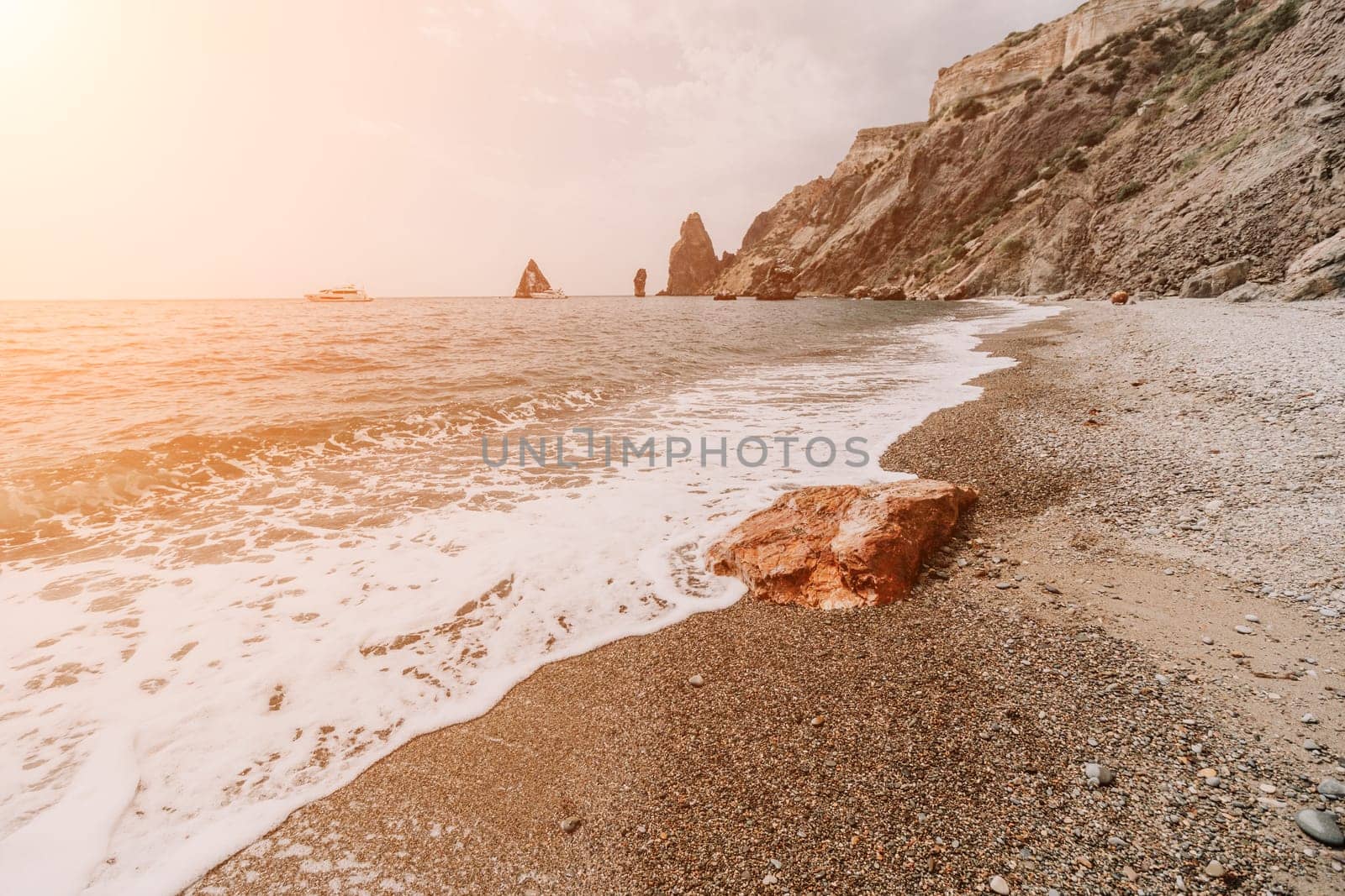 Large red jasper rock on the beach, with the sea in the background. Big Red Jasper Stone Close Up by panophotograph