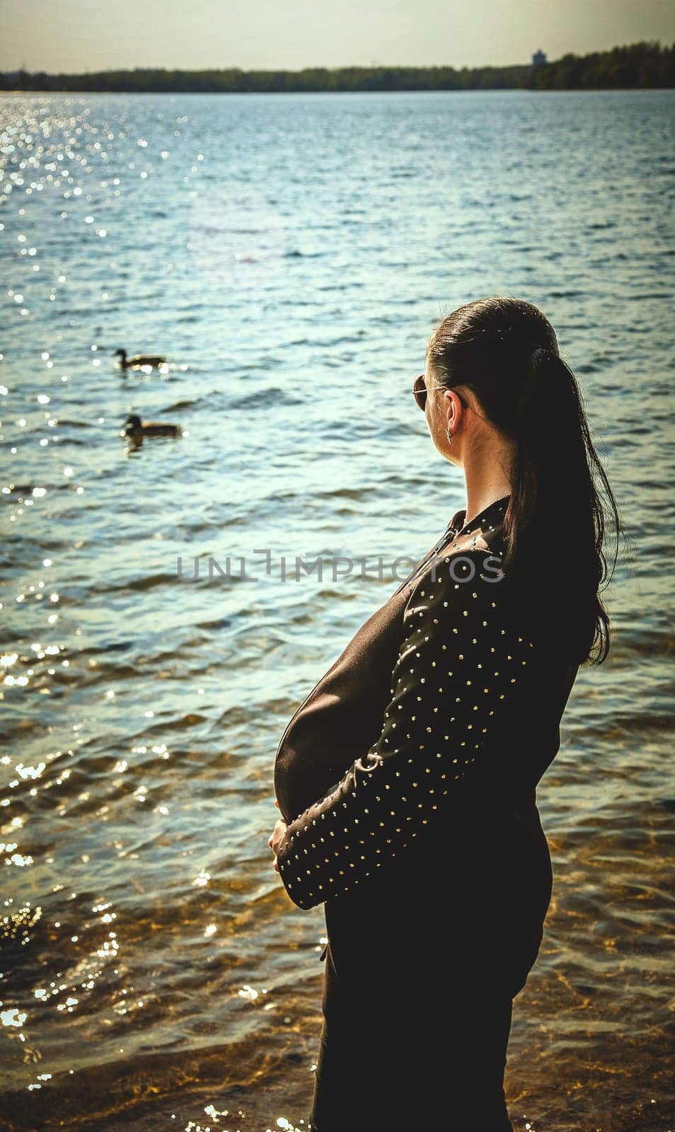 Pregnant brunette girl in sunglasses watching ducks