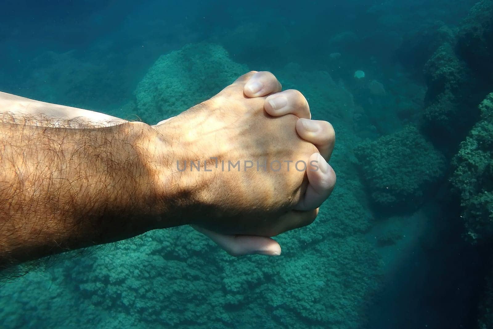 man and woman crossed human hands underwater detail by AndreaIzzotti