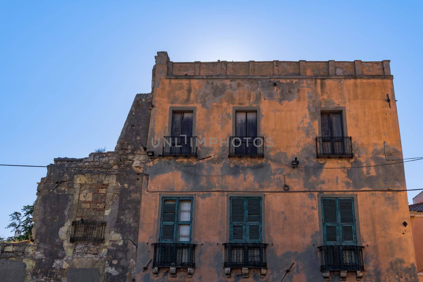 Cagliari citadel old building facade with wooden window shutters, iron balconies and decayed facade in Sardinia Island, Italy.
