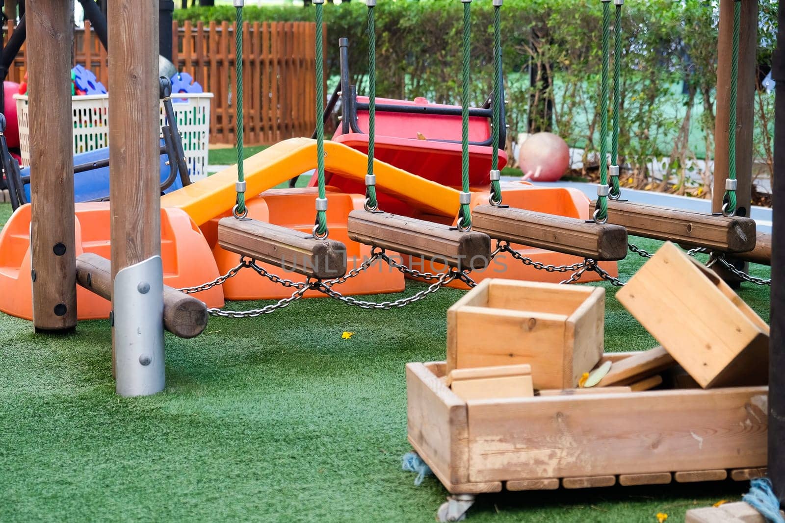 Empty playground with various equipment and toys on green synthetic grass by ponsulak