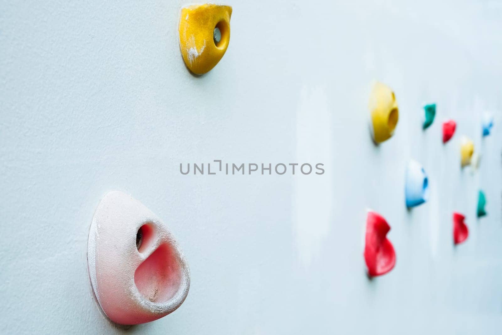 Colorful climbing holds on wall for outdoor rock climbing by ponsulak